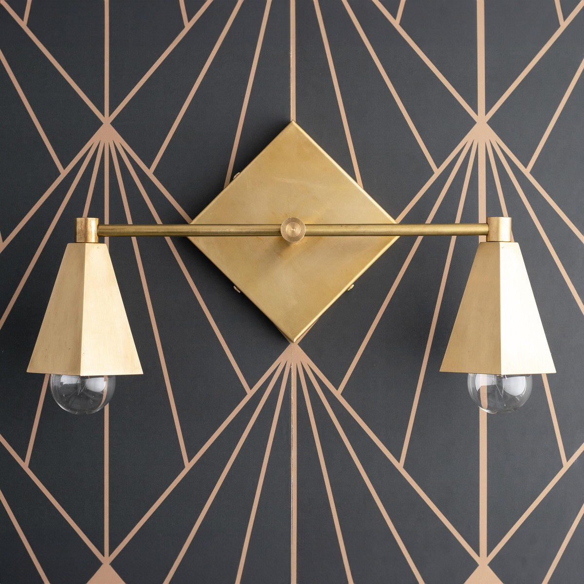 Two-bulb vanity light with raw brass finish and conical shades on geometric dark wall background. - VANITY LIGHT MODEL NO. 4237