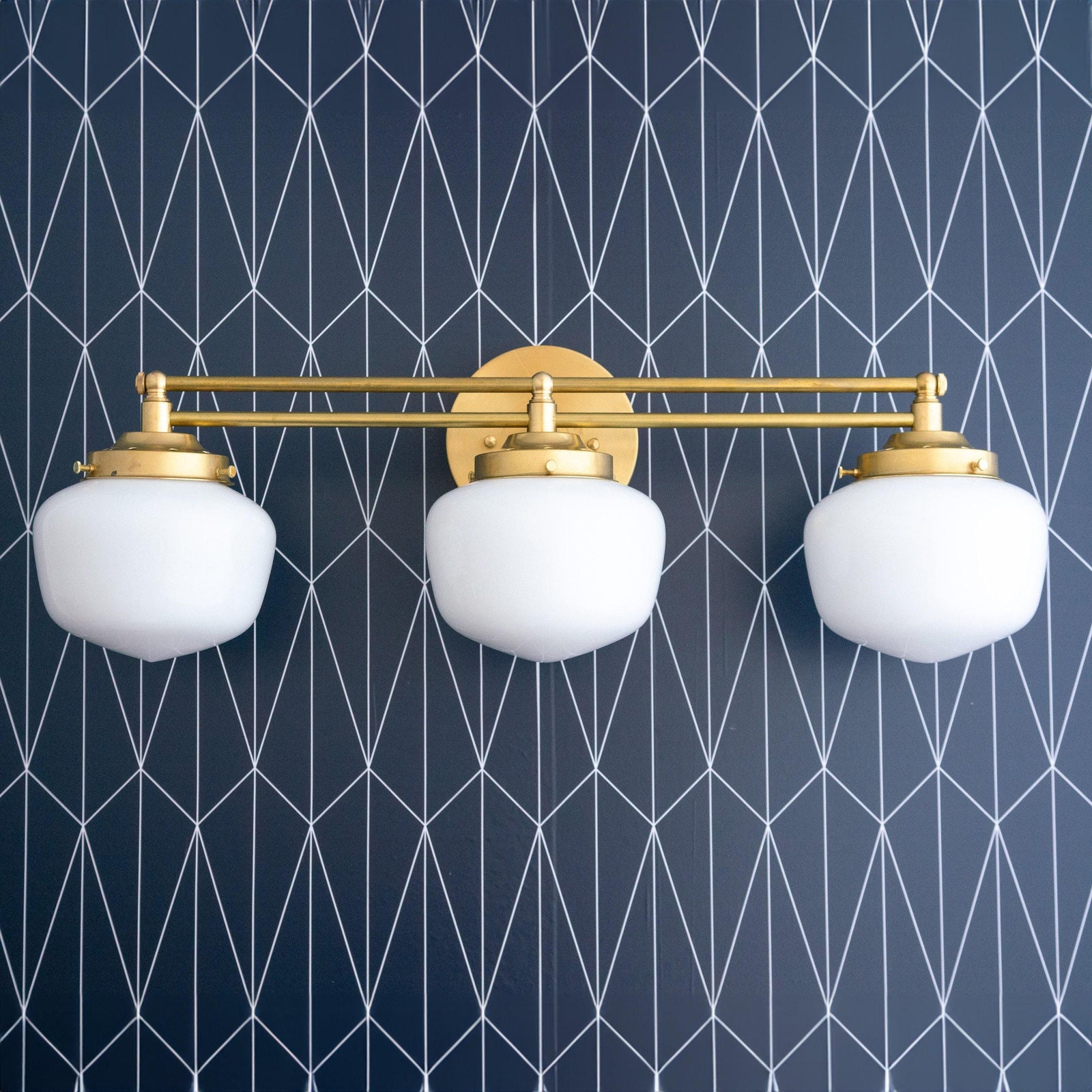 Art Deco 3-bulb vanity light in polished brass with white globe shades against navy geometric wall. - VANITY LIGHT MODEL NO. 4352