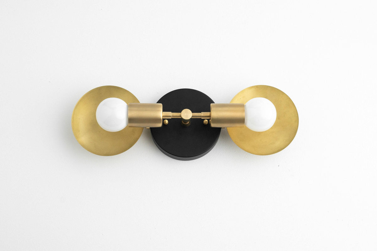 Mid-century modern two-bulb vanity light with raw brass shades and black circular base. - VANITY LIGHT MODEL NO. 2945