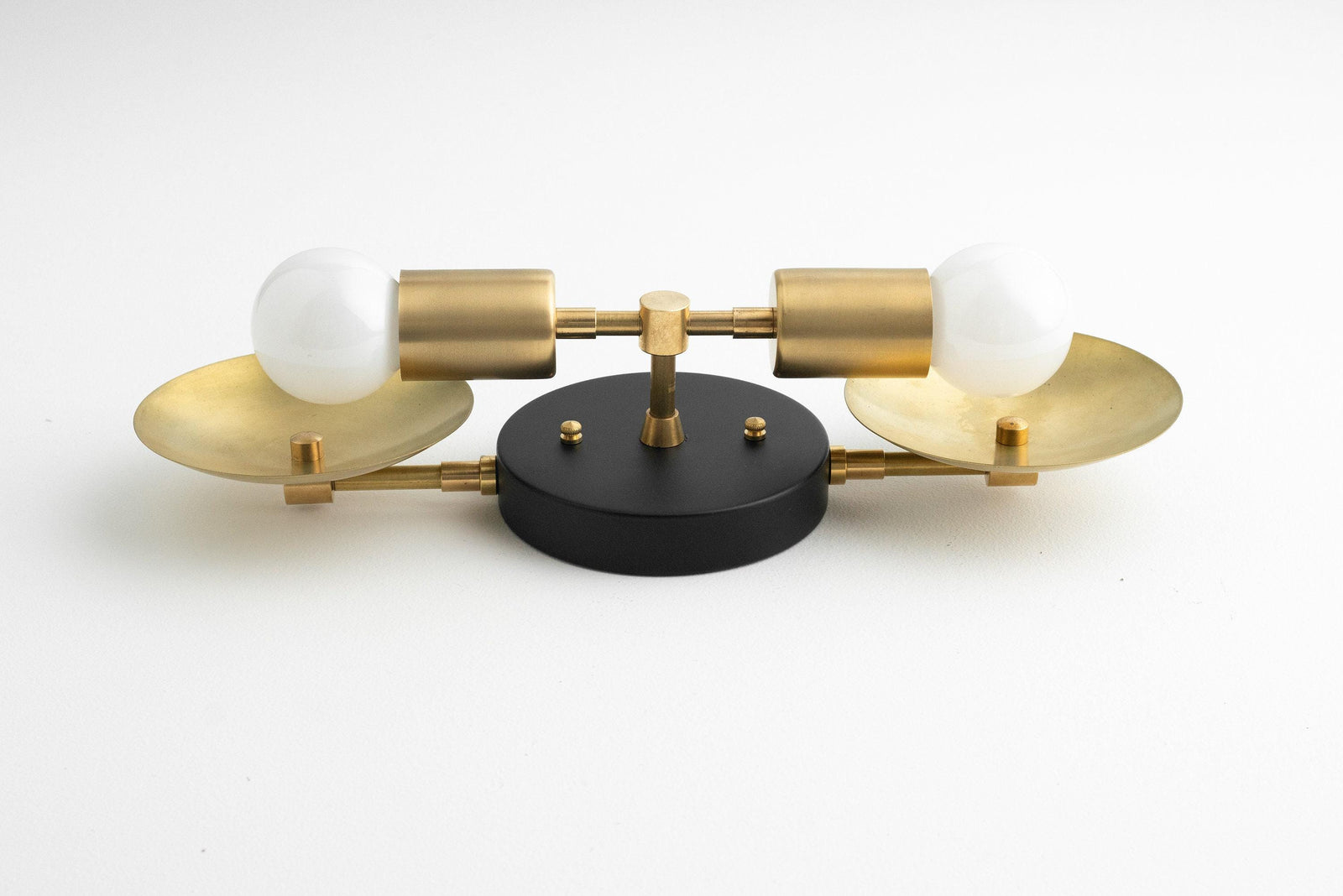 Mid-century modern 2-bulb vanity light with raw brass finish and round black mounting plate. - VANITY LIGHT MODEL NO. 2945