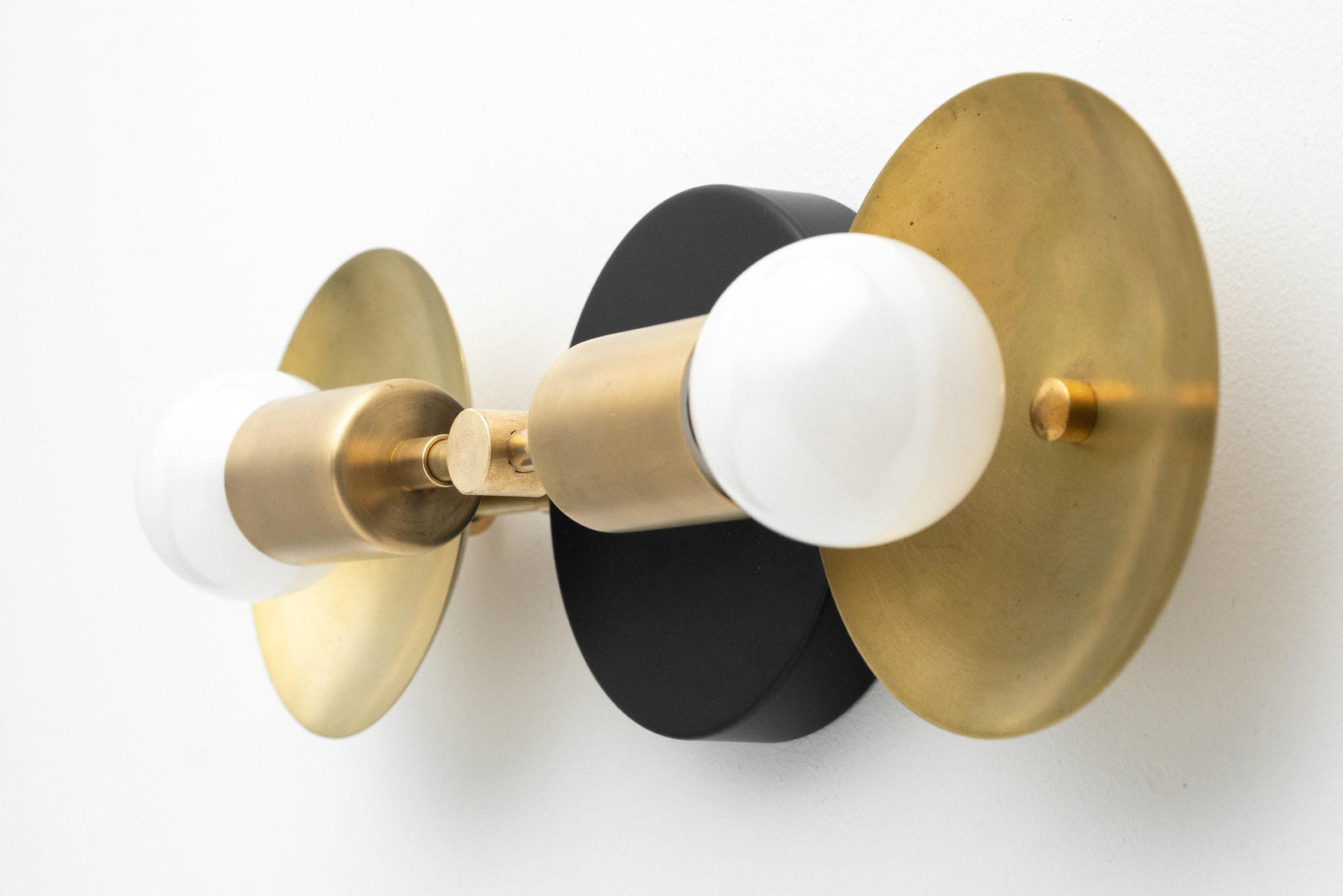 Mid-century modern 2-bulb vanity light with raw brass and black circular backplates and exposed white bulbs. - VANITY LIGHT MODEL NO. 2945