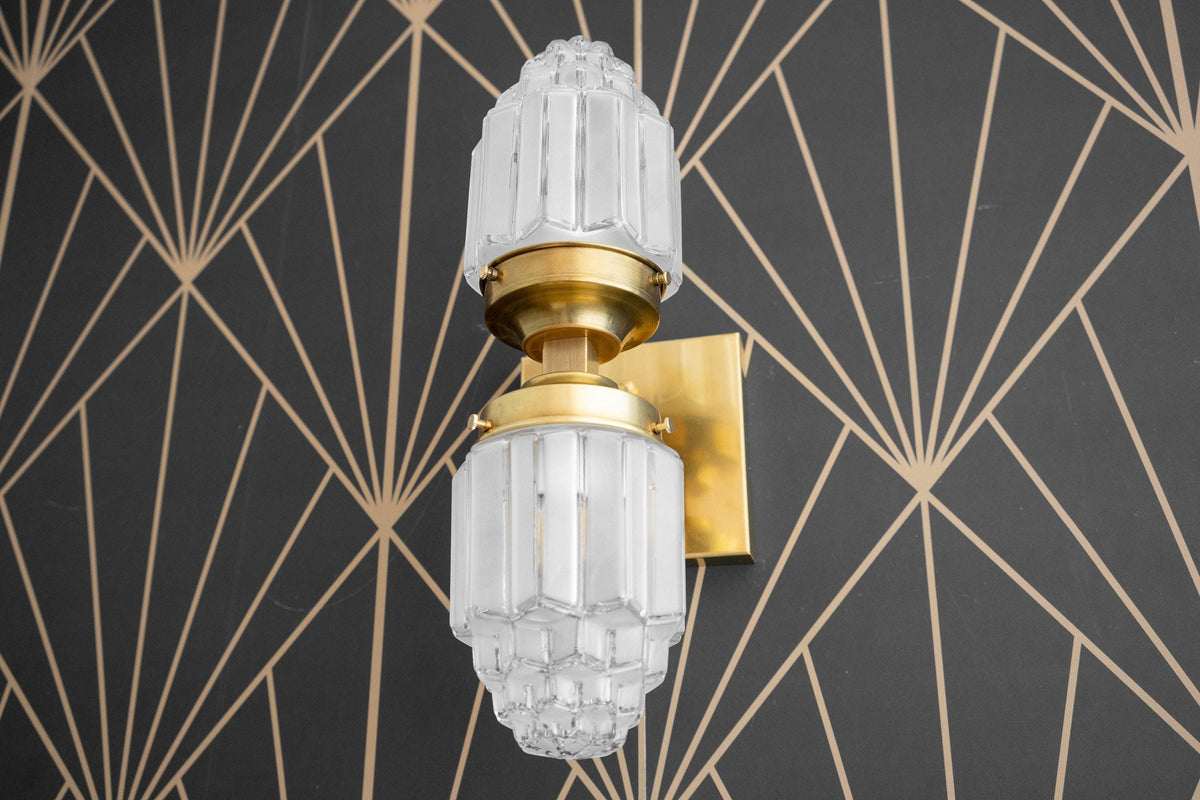 Art Deco style wall sconce with frosted glass globe and polished brass fixture on geometric black and gold background. - SCONCE MODEL NO. 7180