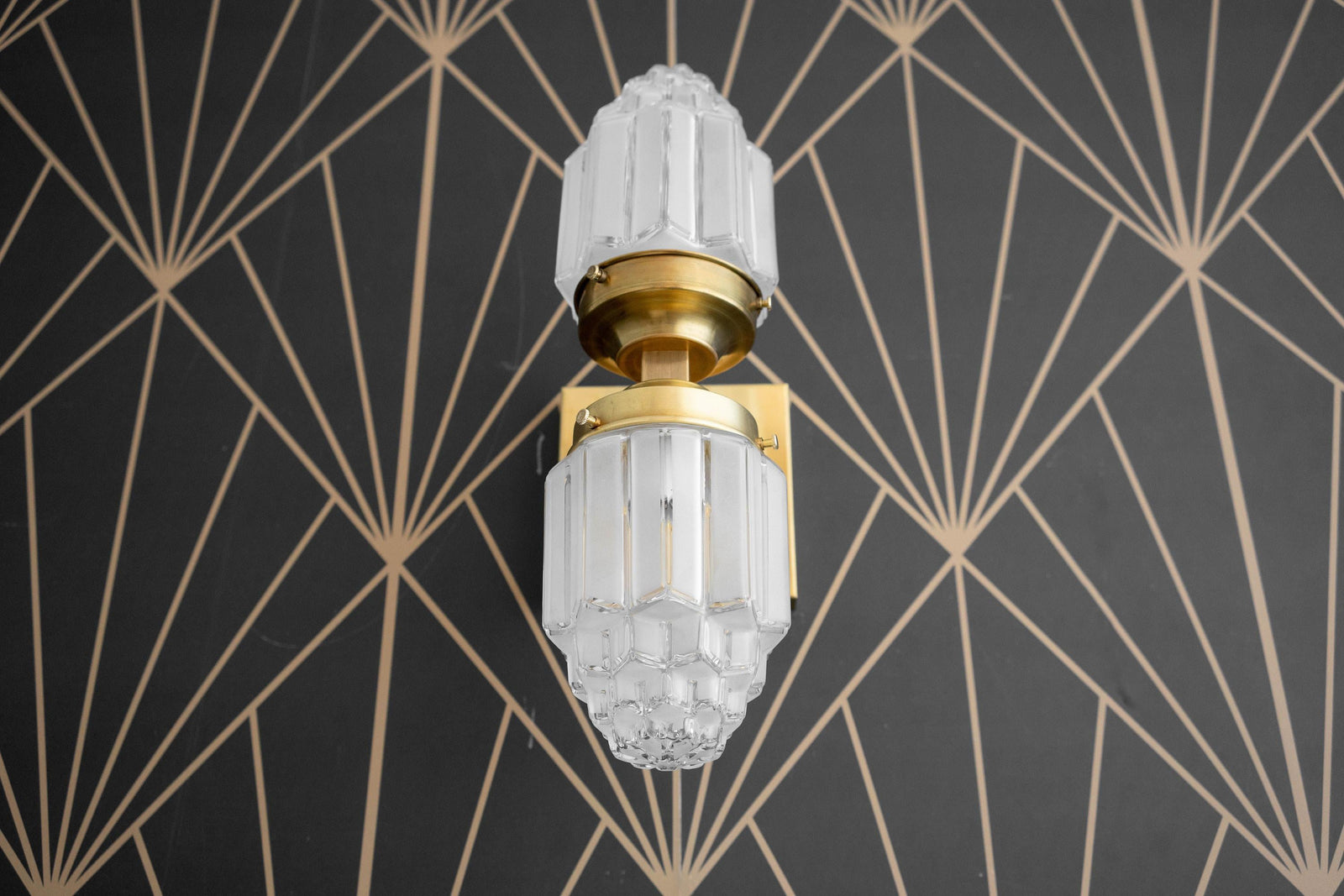 Art Deco wall sconce with dual frosted glass globes and polished brass finish against geometric black wallpaper. - SCONCE MODEL NO. 7180
