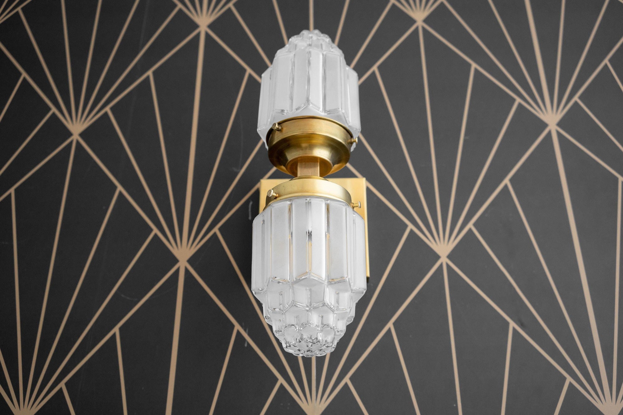 Art Deco wall sconce with dual frosted glass globes and polished brass finish against geometric black wallpaper. - SCONCE MODEL NO. 7180