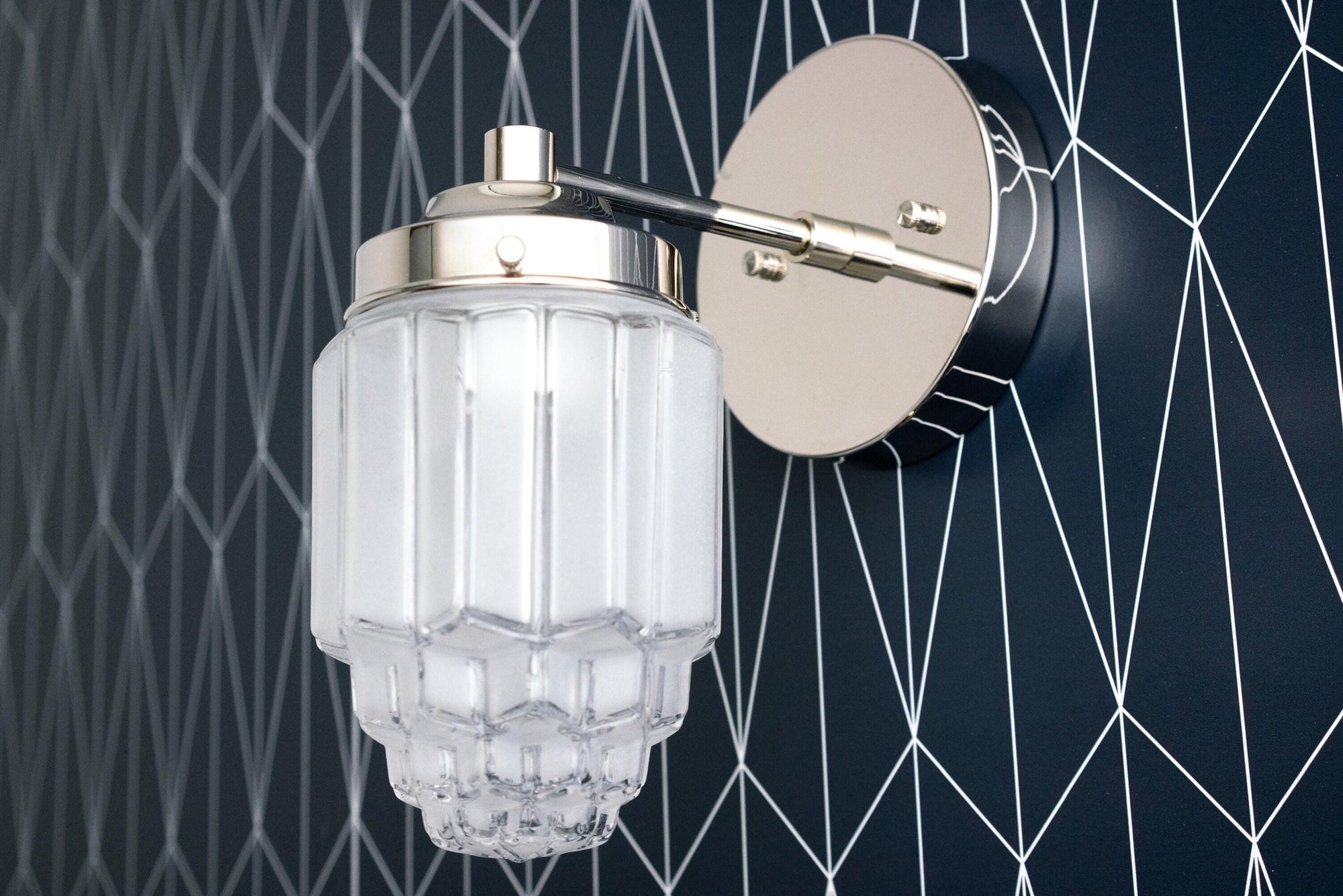 Polished nickel Art Deco wall sconce with clear glass globe and ribbed texture on geometric black wall background. - SCONCE MODEL NO. 6130
