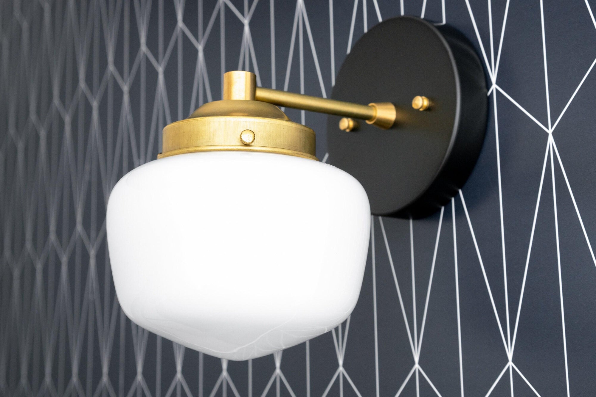 Art Deco wall sconce with white globe shade and raw brass hardware on black circular mount. - SCONCE MODEL NO. 7321