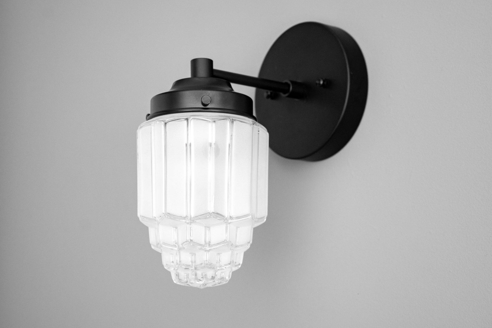 Art Deco black metal sconce with ribbed clear glass globe and round wall mount. - SCONCE MODEL NO. 6130