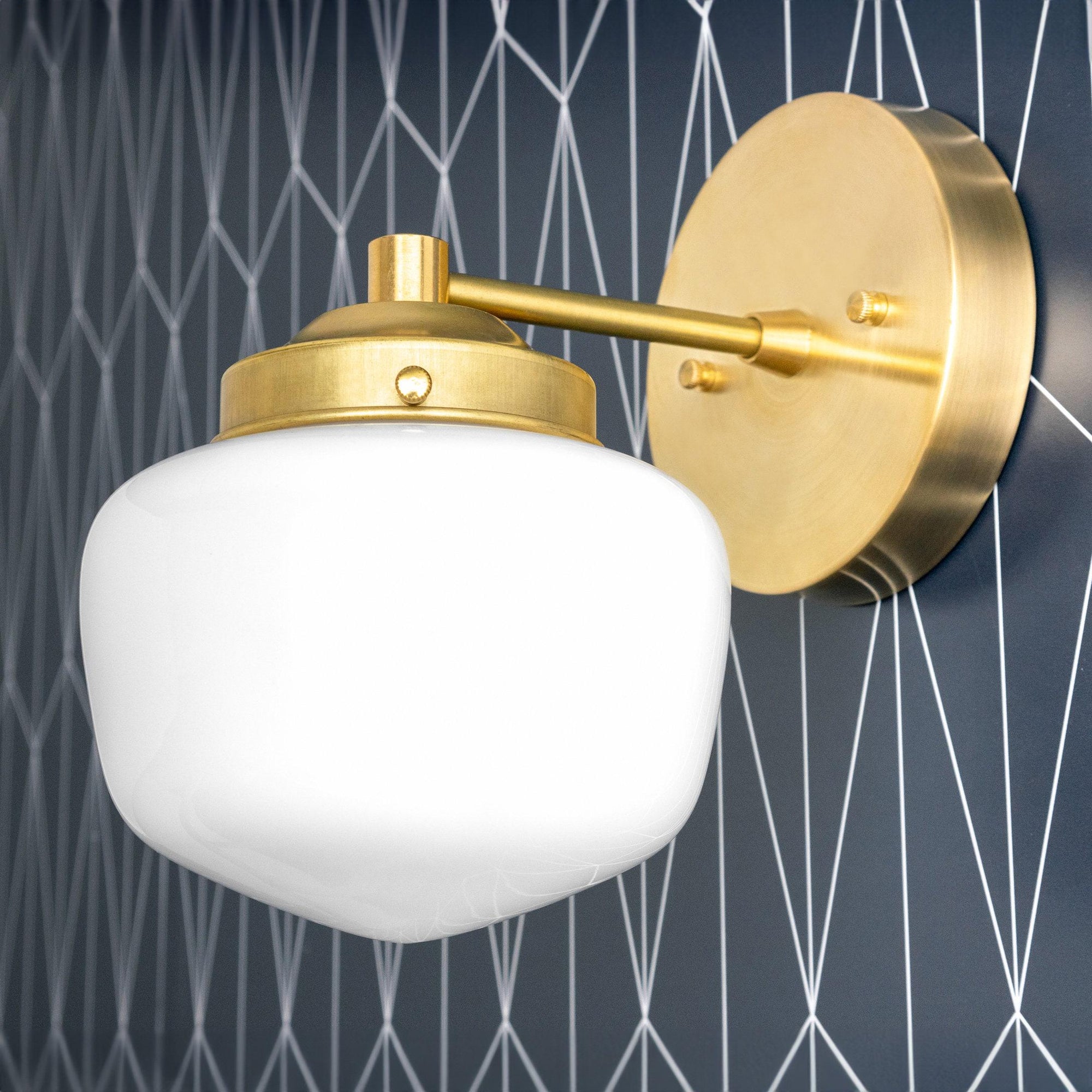 Art Deco wall sconce with raw brass finish and white globe shade mounted on geometric patterned dark wall. - SCONCE MODEL NO. 7321
