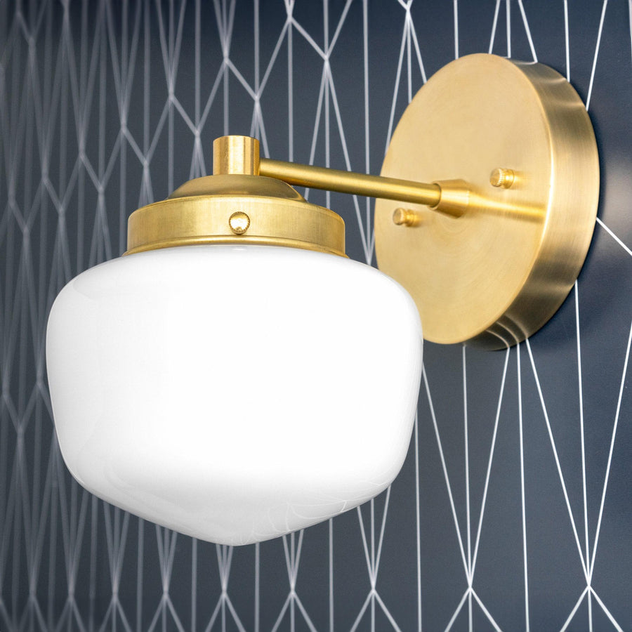 Art Deco wall sconce with raw brass finish and white globe shade mounted on geometric patterned dark wall. - SCONCE MODEL NO. 7321