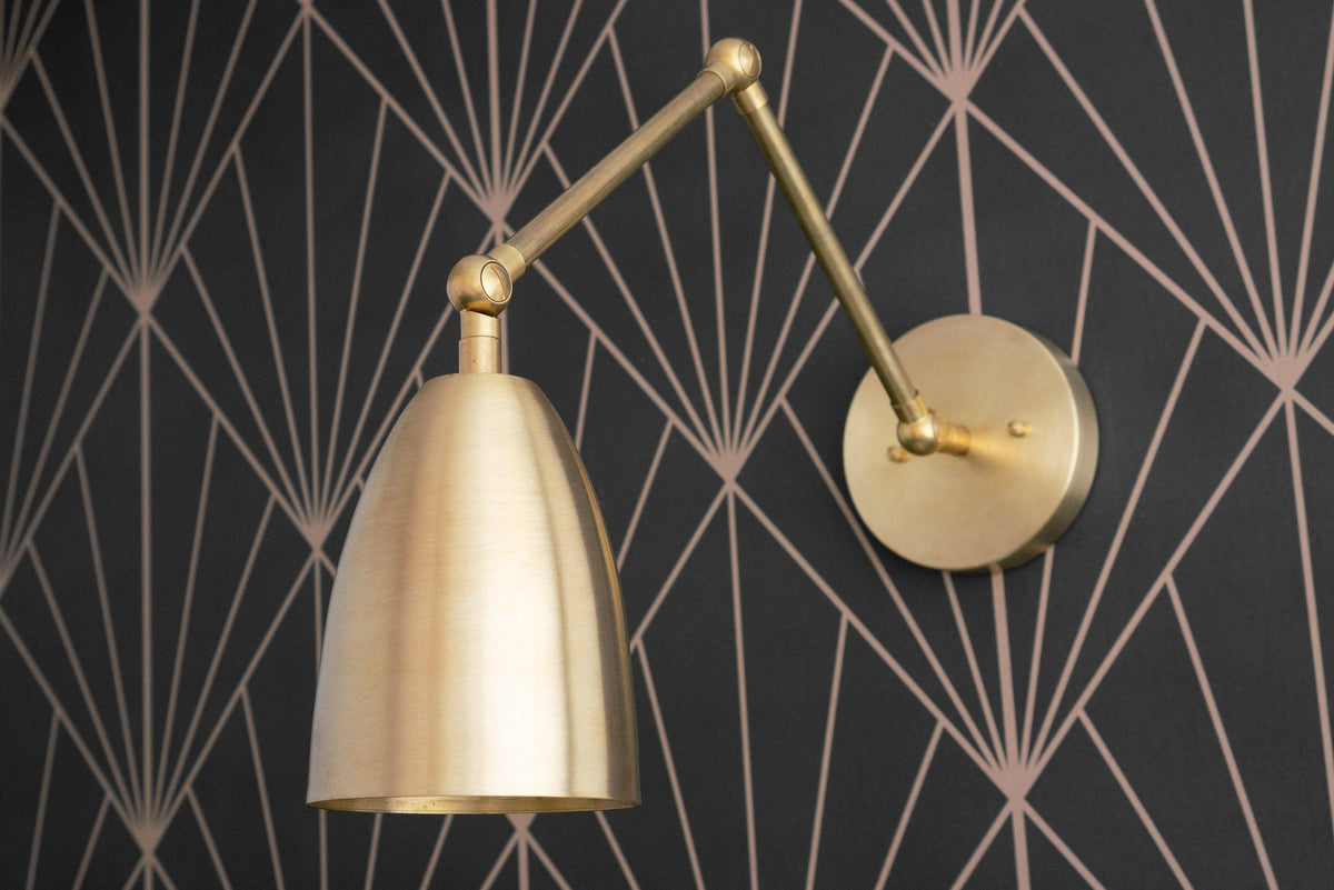 Adjustable raw brass Art Deco wall sconce with dome-shaped shade and swivel arm on geometric black wall. - SCONCE MODEL NO. 0107