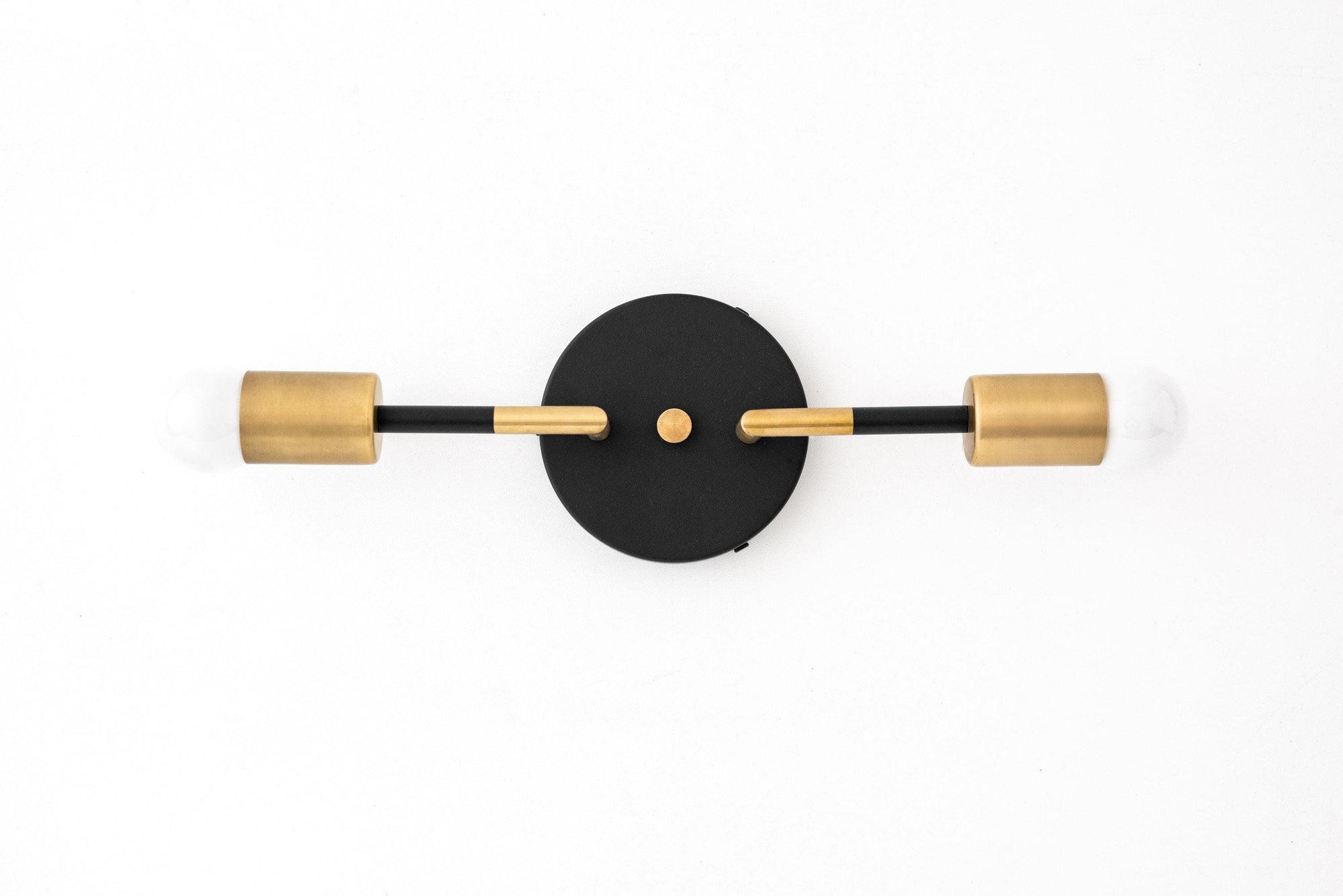 Art Deco two-bulb vanity light with raw brass cylindrical shades and matte black round wall mount. - VANITY LIGHT MODEL NO. 1938