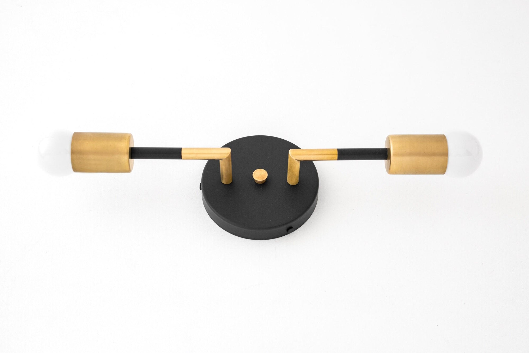 Art Deco vanity light with black circular mount and two exposed bulbs with raw brass cylindrical sockets. - VANITY LIGHT MODEL NO. 1938