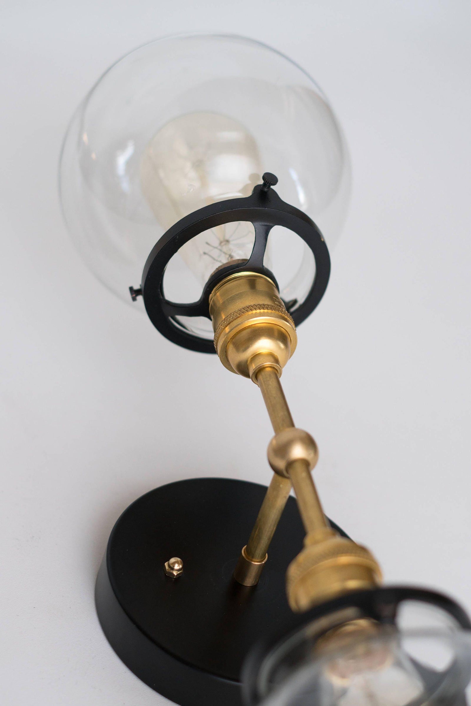 Mid-century modern vanity light with clear globe, black base, and raw brass arm. - VANITY LIGHT MODEL NO. 7350