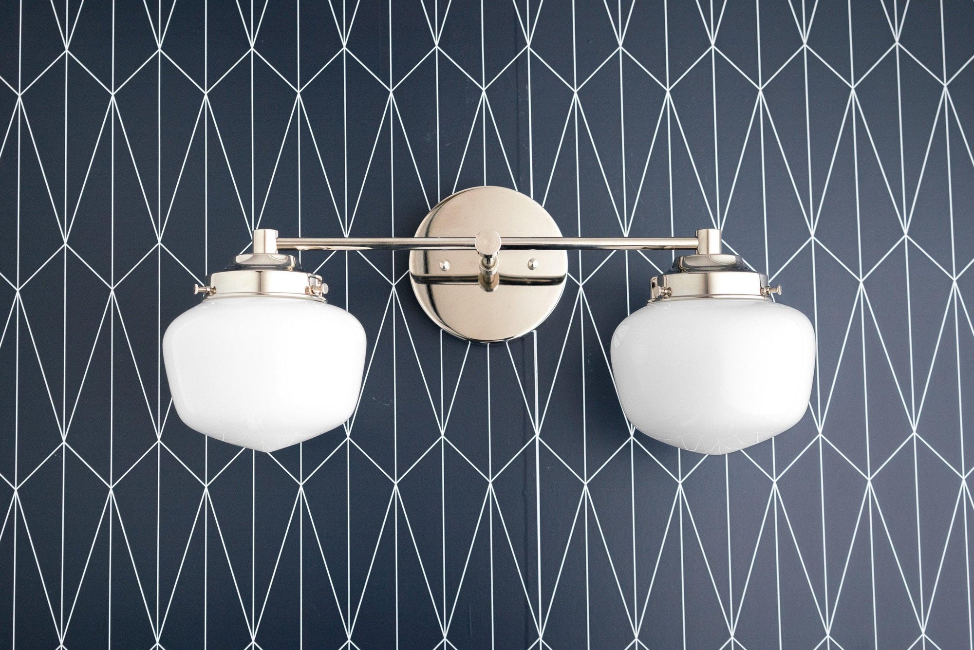 Mid-century modern vanity light with two white globe shades and brushed nickel finish mounted on geometric patterned wall. - VANITY LIGHT MODEL NO. 5799