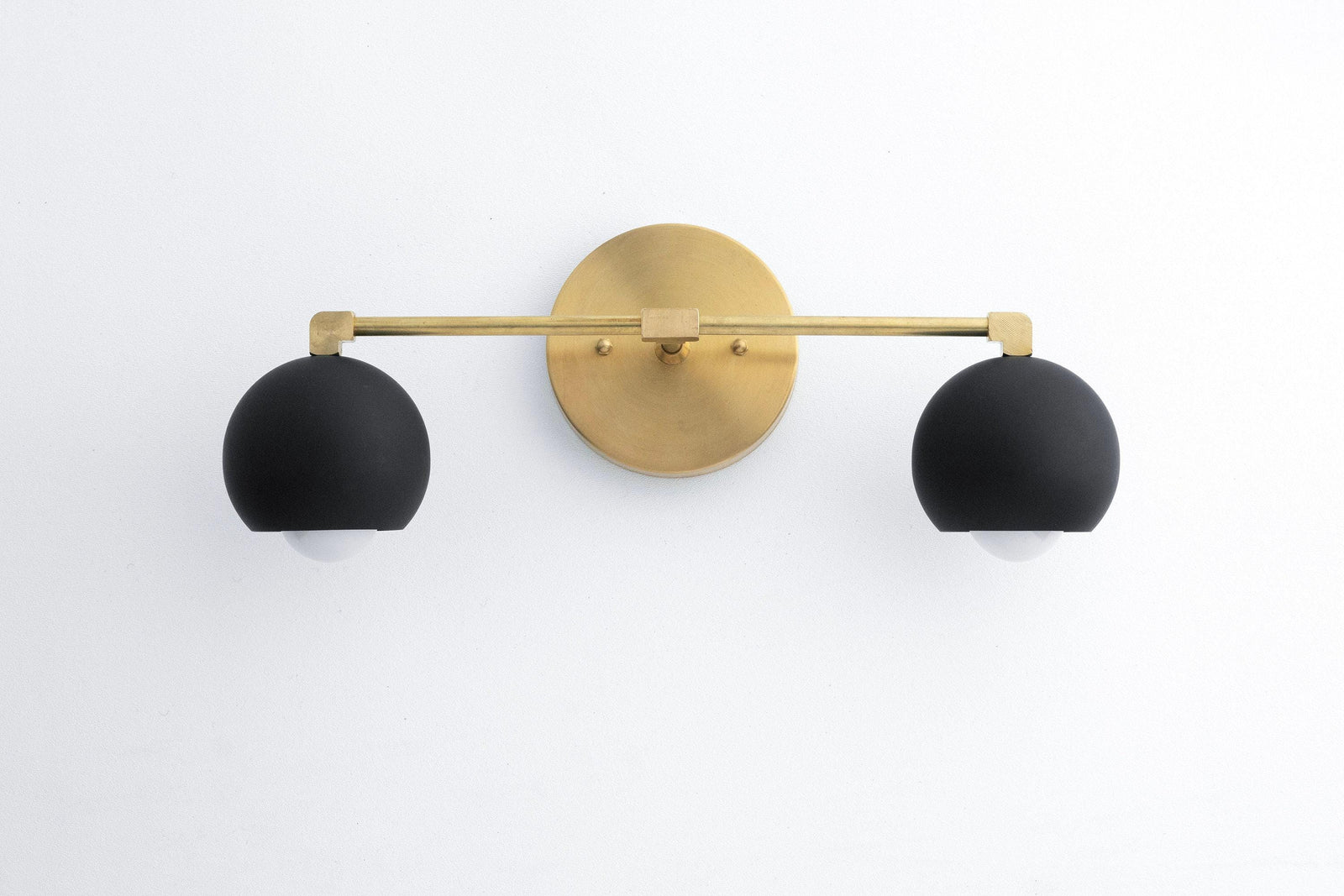 Mid-century modern vanity light with black matte double globes and raw brass horizontal bar mounting. - VANITY LIGHT MODEL NO. 5469