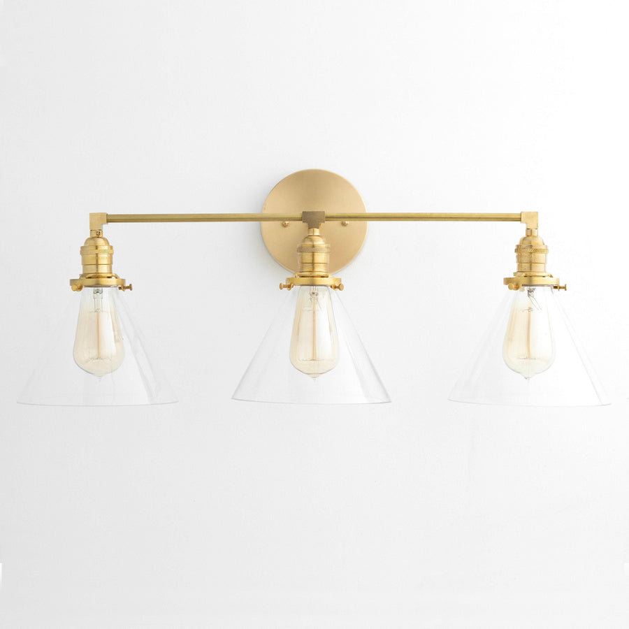 Mid-century modern 3-bulb vanity light with raw brass finish and clear glass conical shades. - VANITY LIGHT MODEL NO. 5219