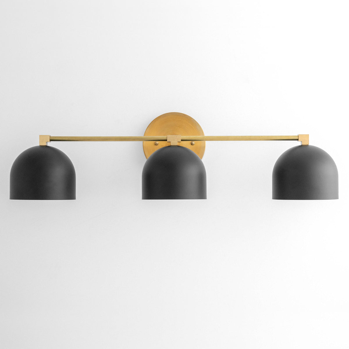 Three-bulb vanity light with black dome shades and brass horizontal bar mounting on wall. - VANITY LIGHT MODEL NO. 7565