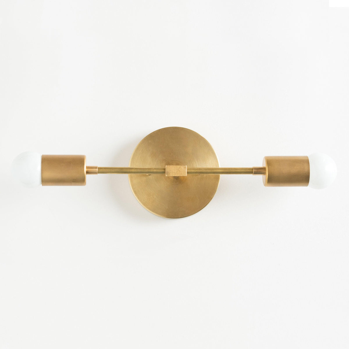 Mid-century modern two-bulb vanity light in raw brass with cylindrical shades and exposed bulbs. - VANITY LIGHT MODEL NO. 5563