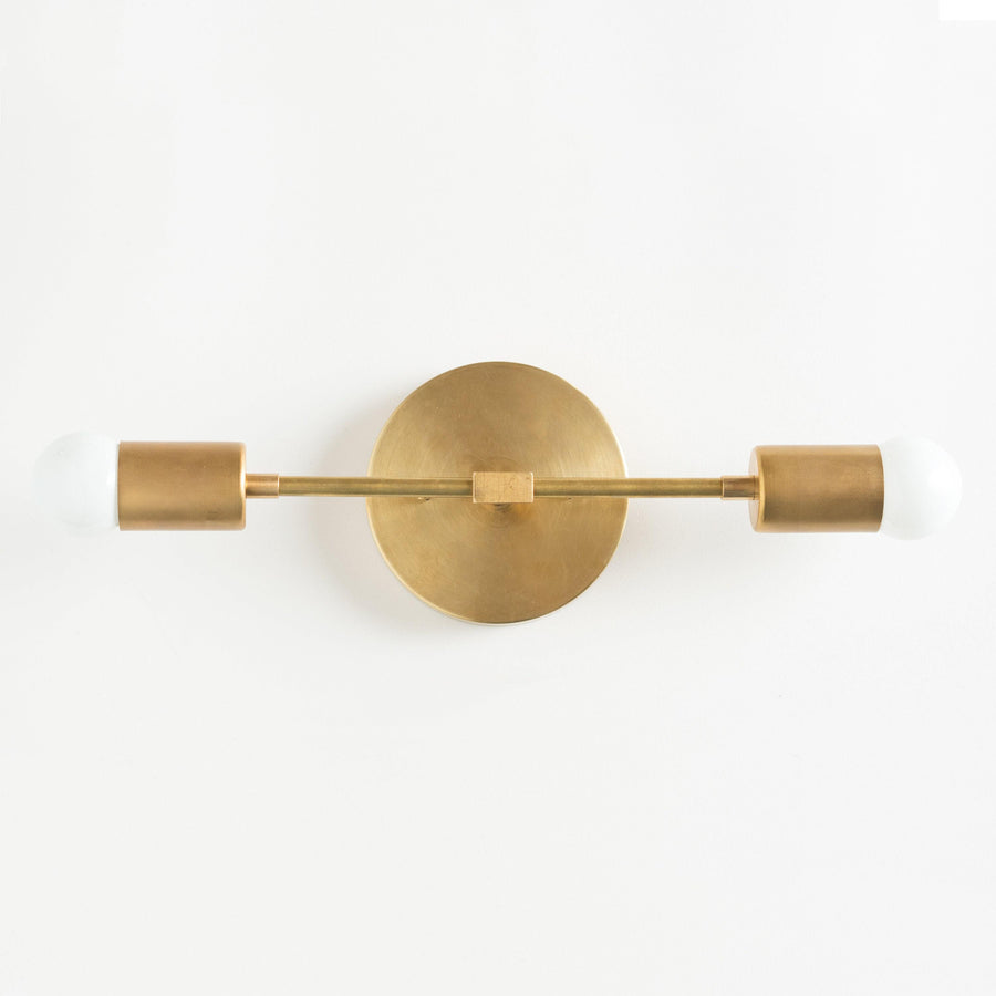 Mid-century modern two-bulb vanity light in raw brass with cylindrical shades and exposed bulbs. - VANITY LIGHT MODEL NO. 5563