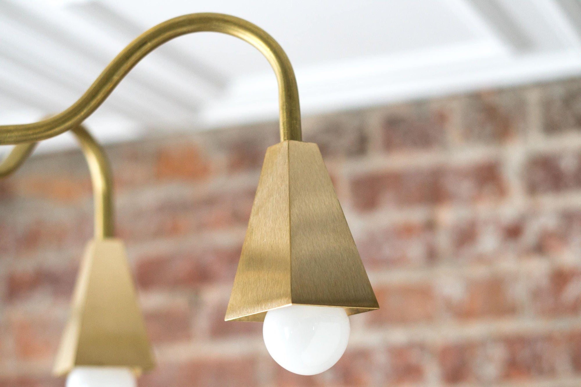 Raw brass mid-century modern chandelier arm with conical socket and exposed bulb against brick wall. - CHANDELIER MODEL NO. 2464