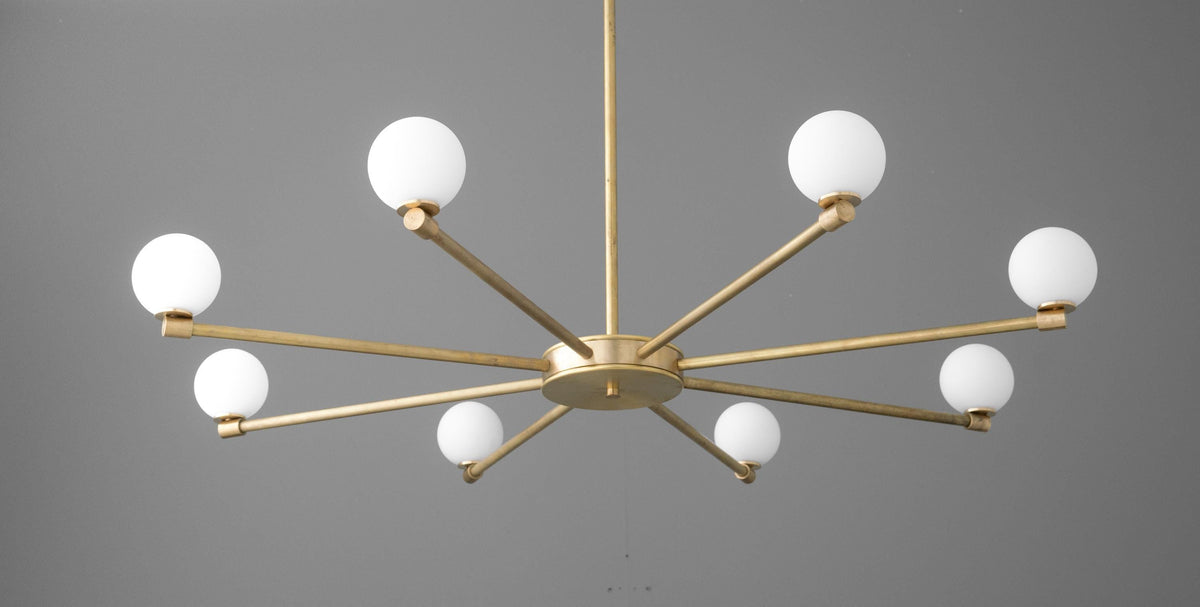 Minimalist raw brass chandelier with eight glowing white glass globes on extended arms. - CHANDELIER MODEL NO. 3192