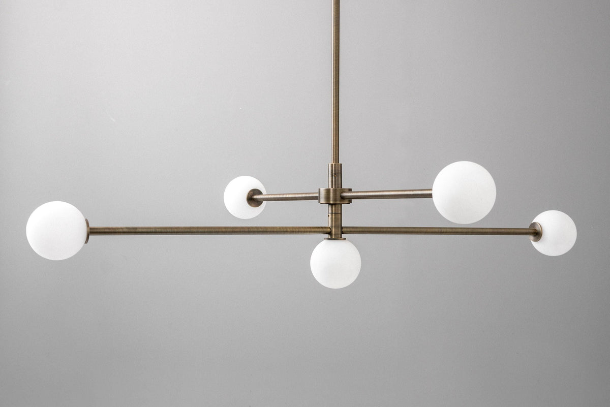 Mid-century modern chandelier with antique brass finish and five white globe lights on a swivel frame. - CHANDELIER MODEL NO. 4577