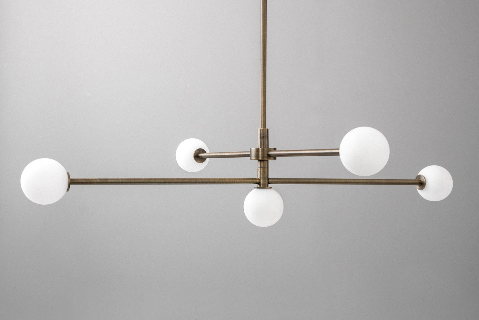 Mid-century modern chandelier with antique brass finish and five white globe lights on a swivel frame. - CHANDELIER MODEL NO. 4577