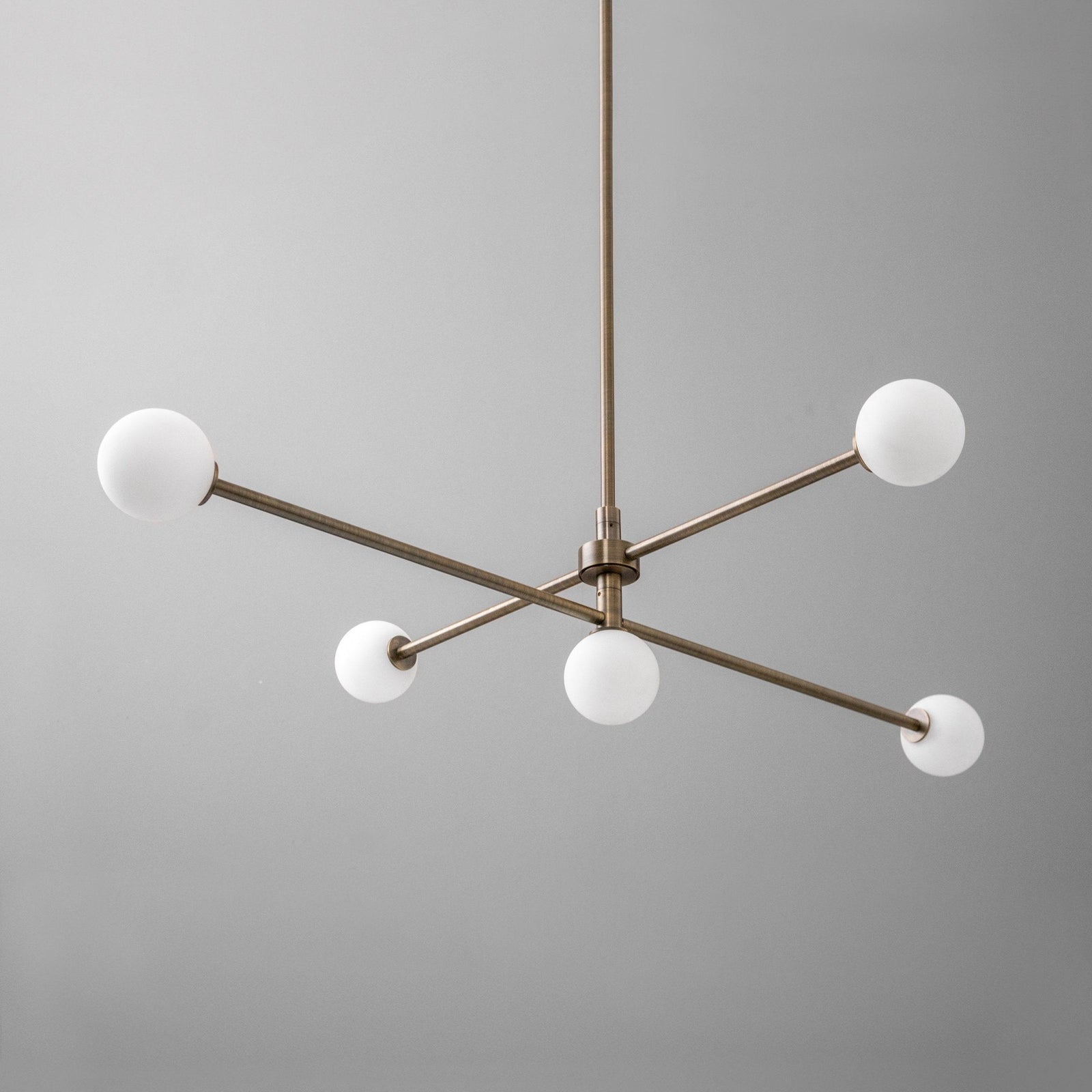 Mid-century modern brass chandelier with four white globe lights and a minimalist swivel design. - CHANDELIER MODEL NO. 4577