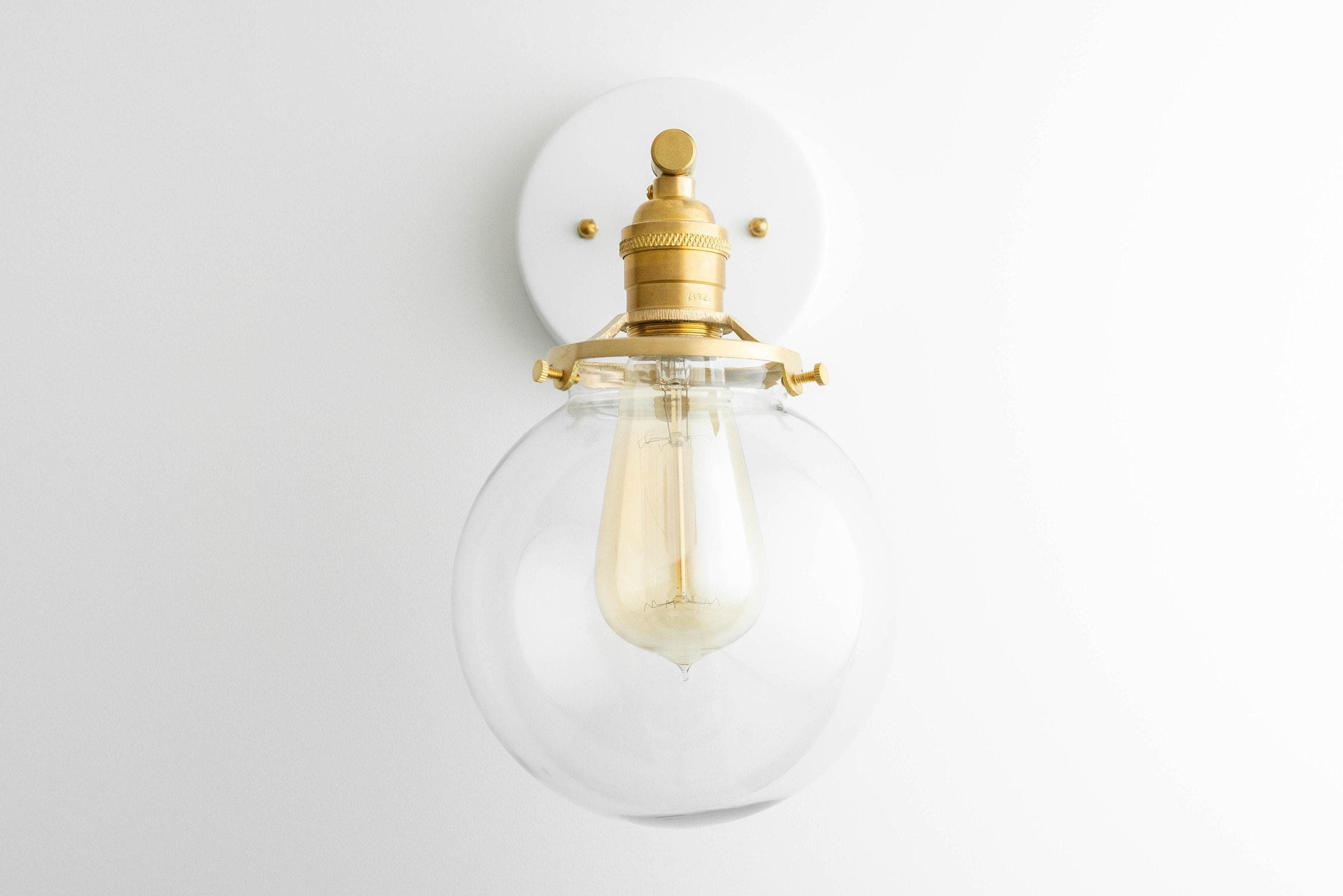 Mid-century modern wall sconce with clear globe and raw brass hardware on white mounting plate. - SCONCE MODEL NO. 5456