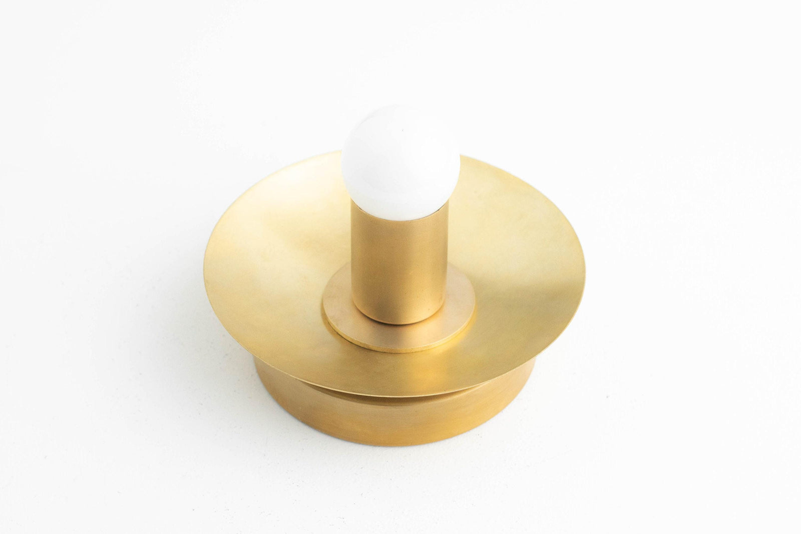 Raw brass Art Deco wall sconce with round backplate and single exposed bulb. - SCONCE MODEL NO. 7004