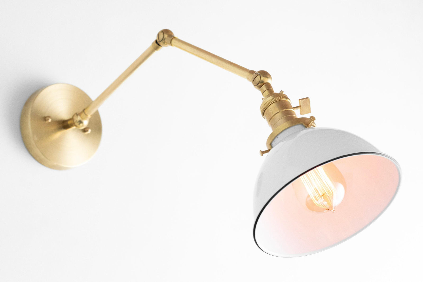 Adjustable mid-century modern wall sconce with raw brass arm and white metal shade with black trim. - SCONCE MODEL NO. 8551