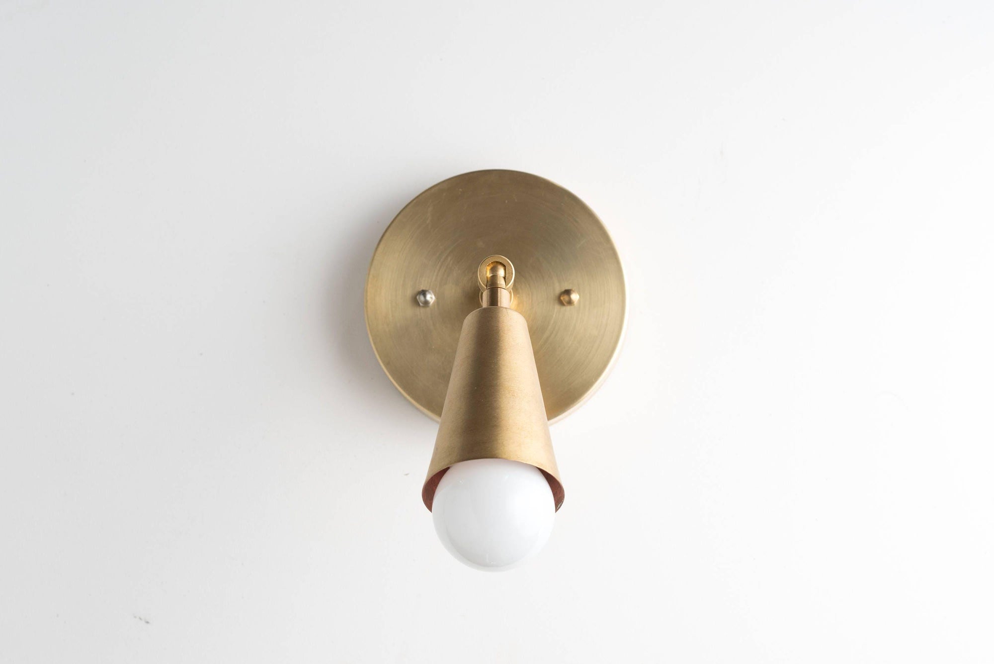 Mid-century modern raw brass adjustable wall sconce with exposed bulb and round backplate. - SCONCE MODEL NO. 4339