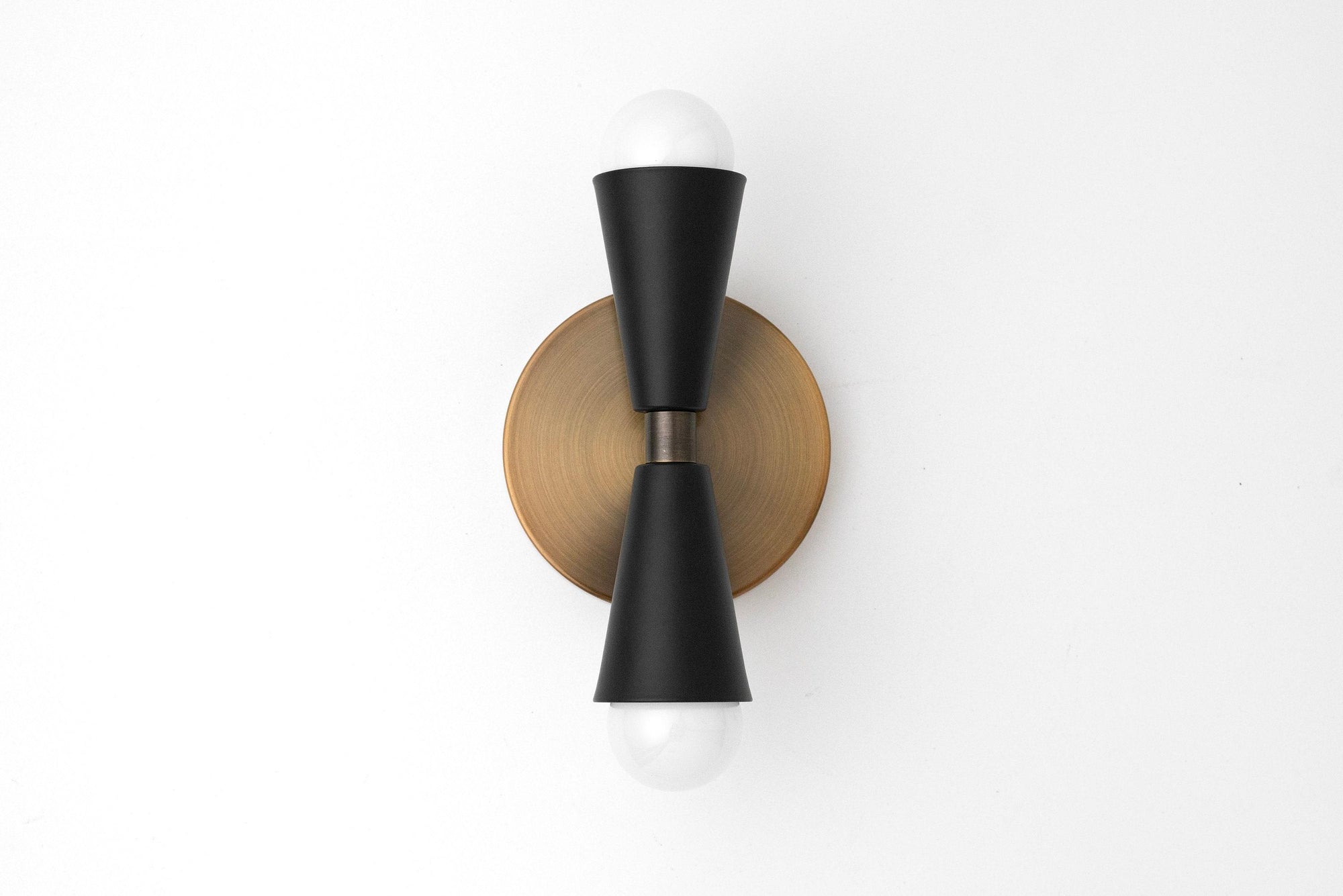 Mid-century modern black double-cone sconce with bare bulbs mounted on round brass base. - SCONCE MODEL NO. 4717