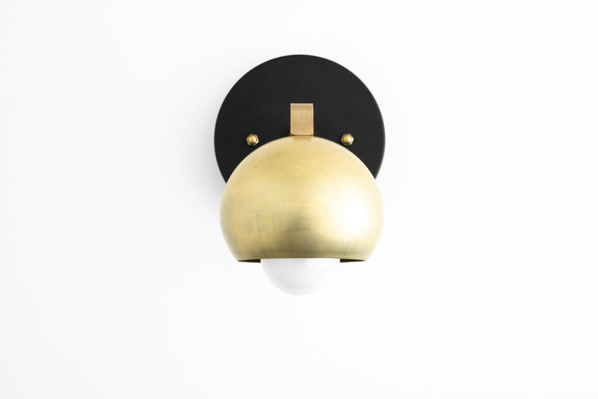 Mid-century modern sconce with raw brass dome shade and black circular backplate. - SCONCE MODEL NO. 0053