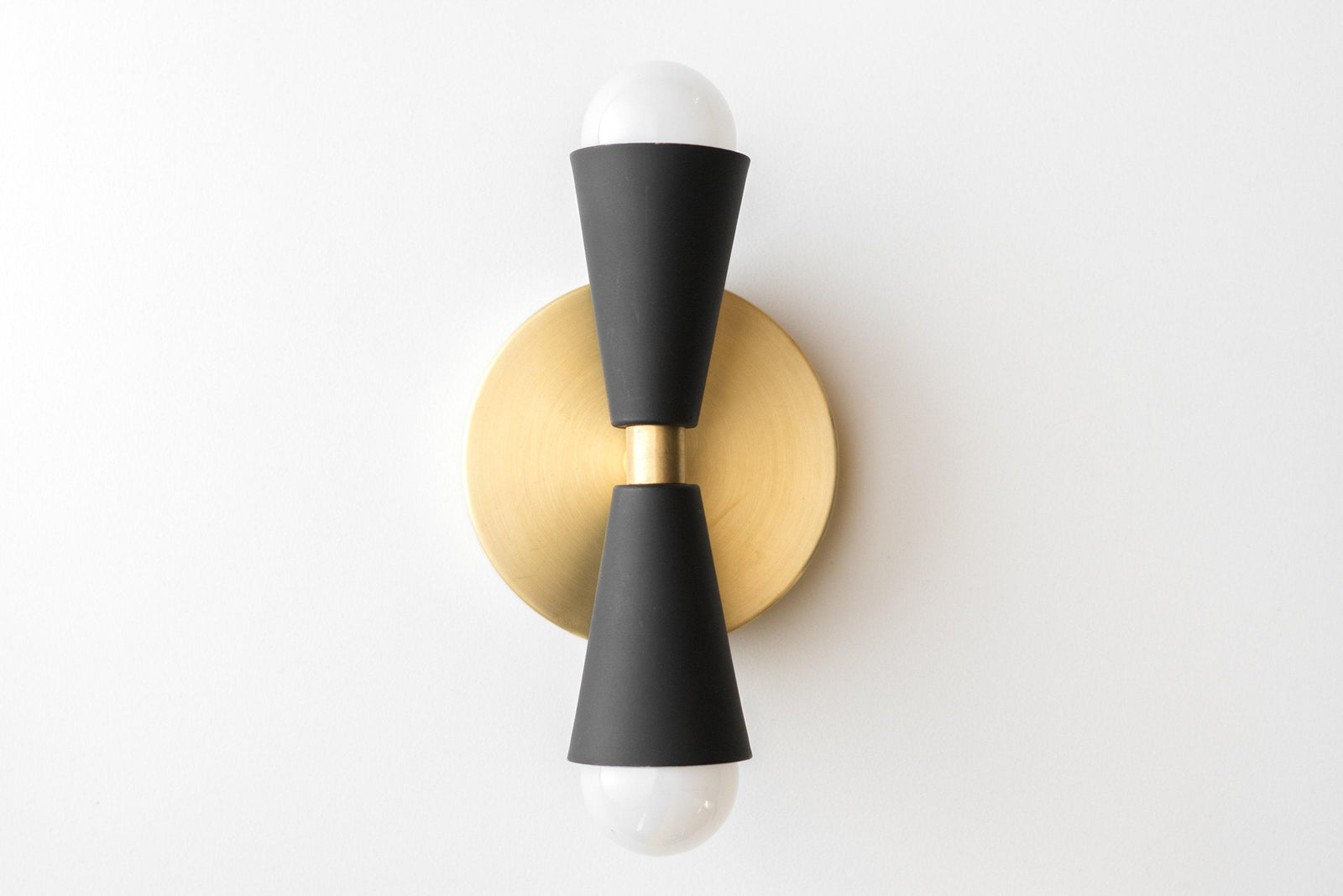 Mid-century modern black up/down sconce with raw brass round wall plate and exposed bulbs. - SCONCE MODEL NO. 4717
