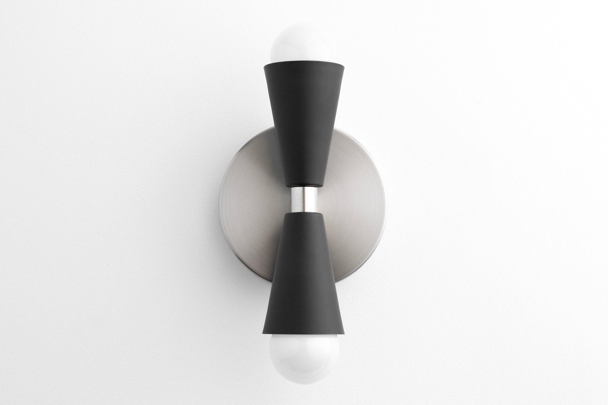 Mid-century modern up/down sconce with brushed nickel base and black tapered cylindrical shades housing exposed bulbs. - SCONCE MODEL NO. 4717