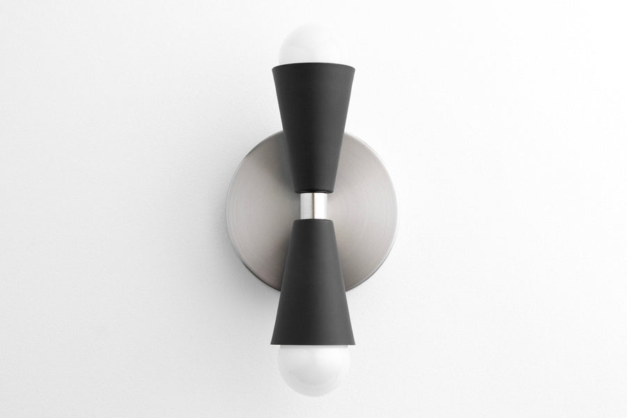 Mid-century modern up/down sconce with brushed nickel base and black tapered cylindrical shades housing exposed bulbs. - SCONCE MODEL NO. 4717