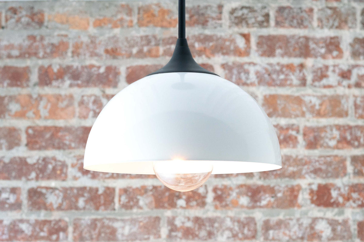 Mid-century modern black and white pendant light with dome-shaped shade and exposed bulb against brick wall. - PENDANT MODEL NO. 9263