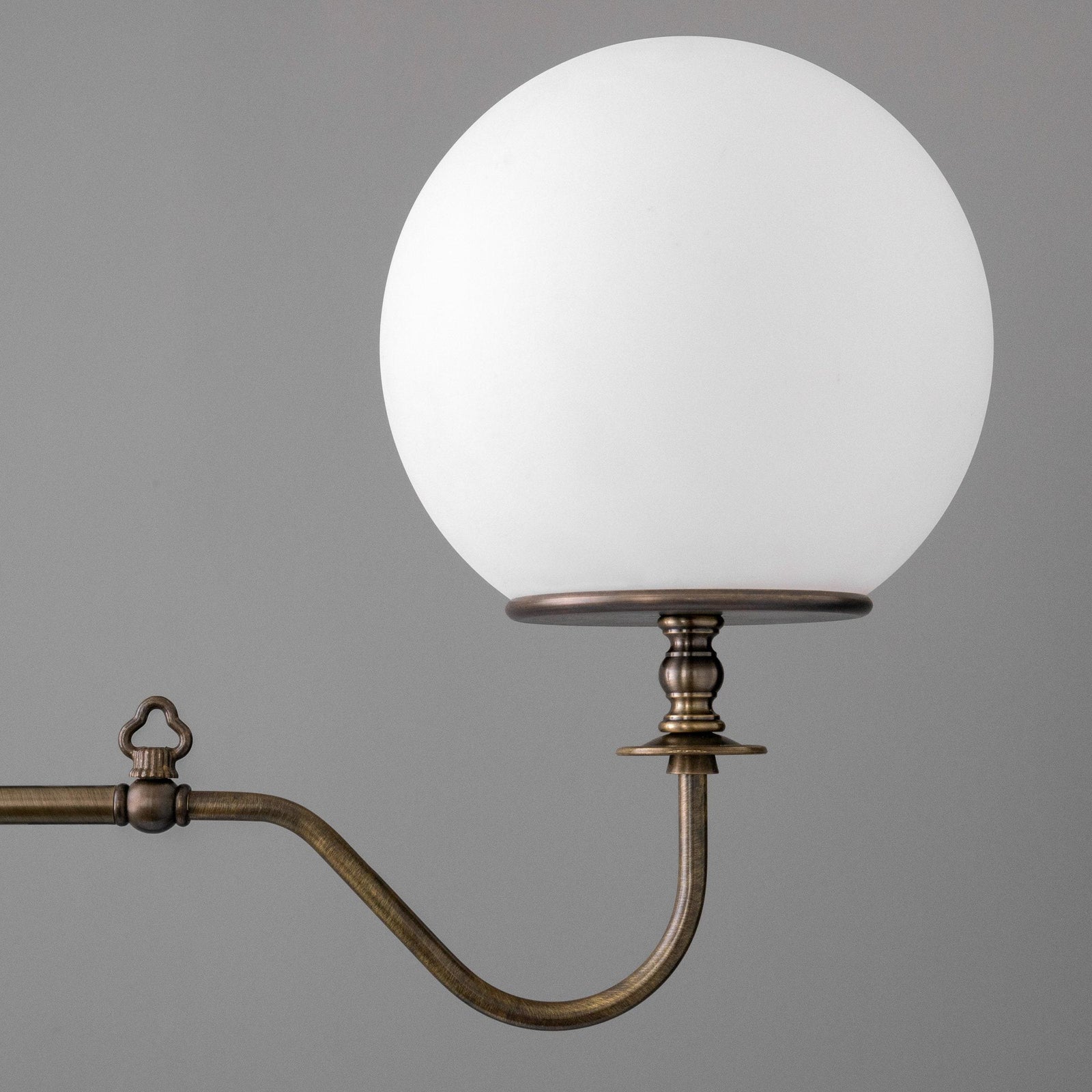 Antique brass industrial chandelier arm with round white globe shade against gray background. - CHANDELIER MODEL NO. 5046