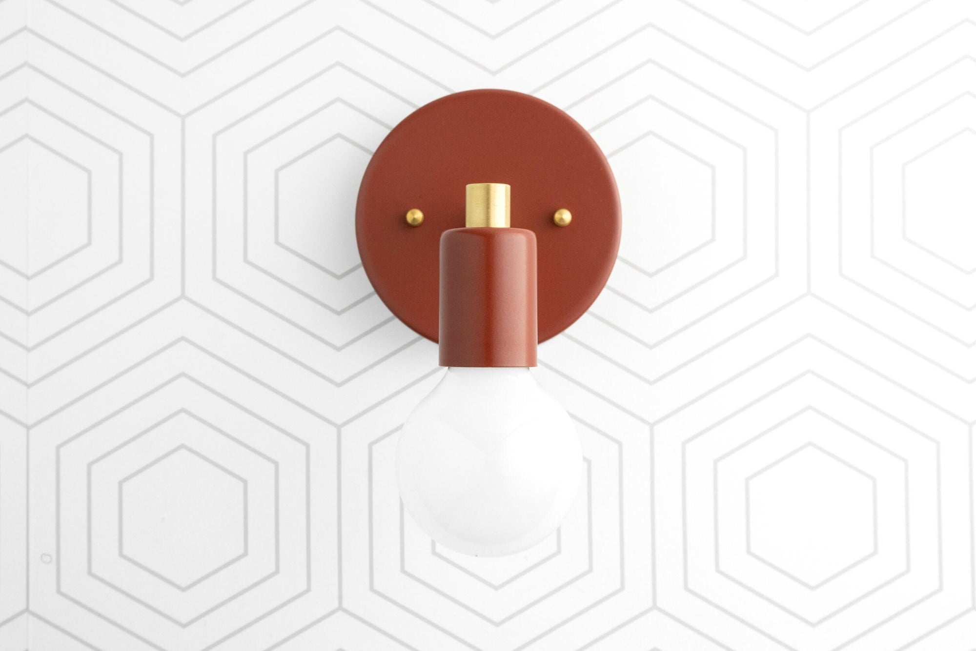 Scandinavian-style wall sconce in raw brass with exposed bulb and rust-colored circular backplate. - SCONCE MODEL NO. 9036