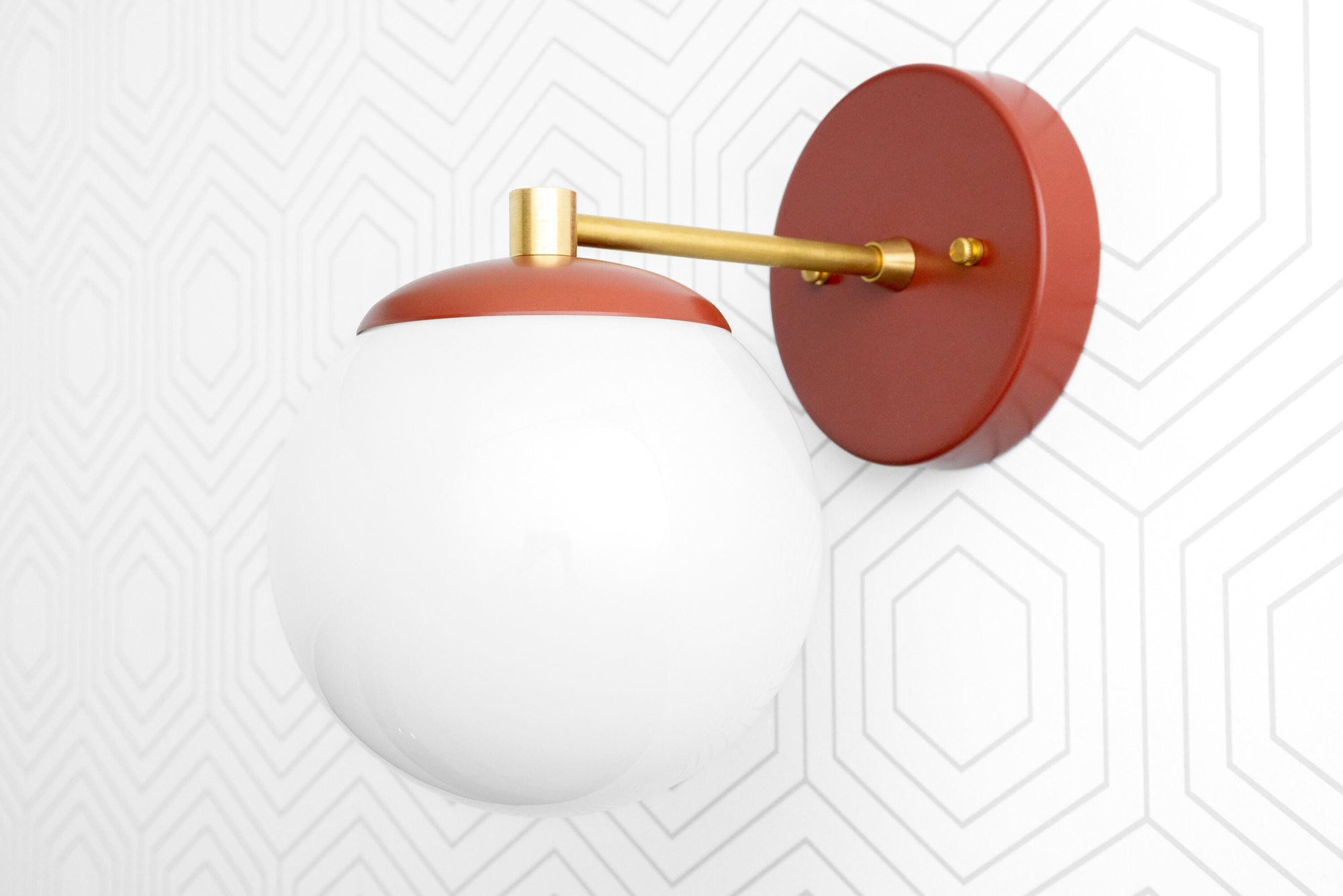 Scandinavian-style wall sconce with matte red base and arm, white globe shade, and brass accents. - SCONCE MODEL NO. 5524