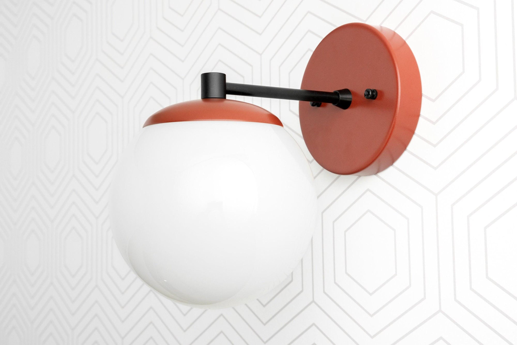 Scandinavian-style sconce with matte black arm and rust-orange canopy holding a white globe shade. - SCONCE MODEL NO. 5524
