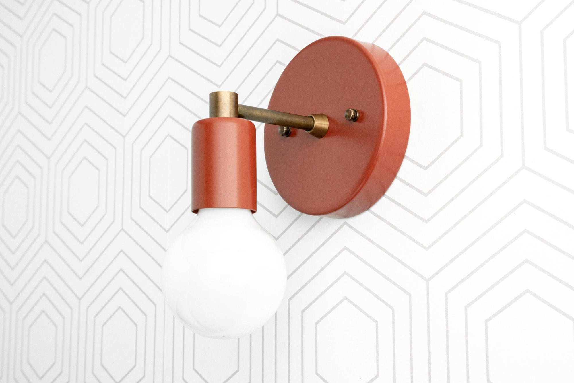 Wall sconce with matte terracotta shade and brass arm mounted on geometric patterned white wall. - SCONCE MODEL NO. 9036