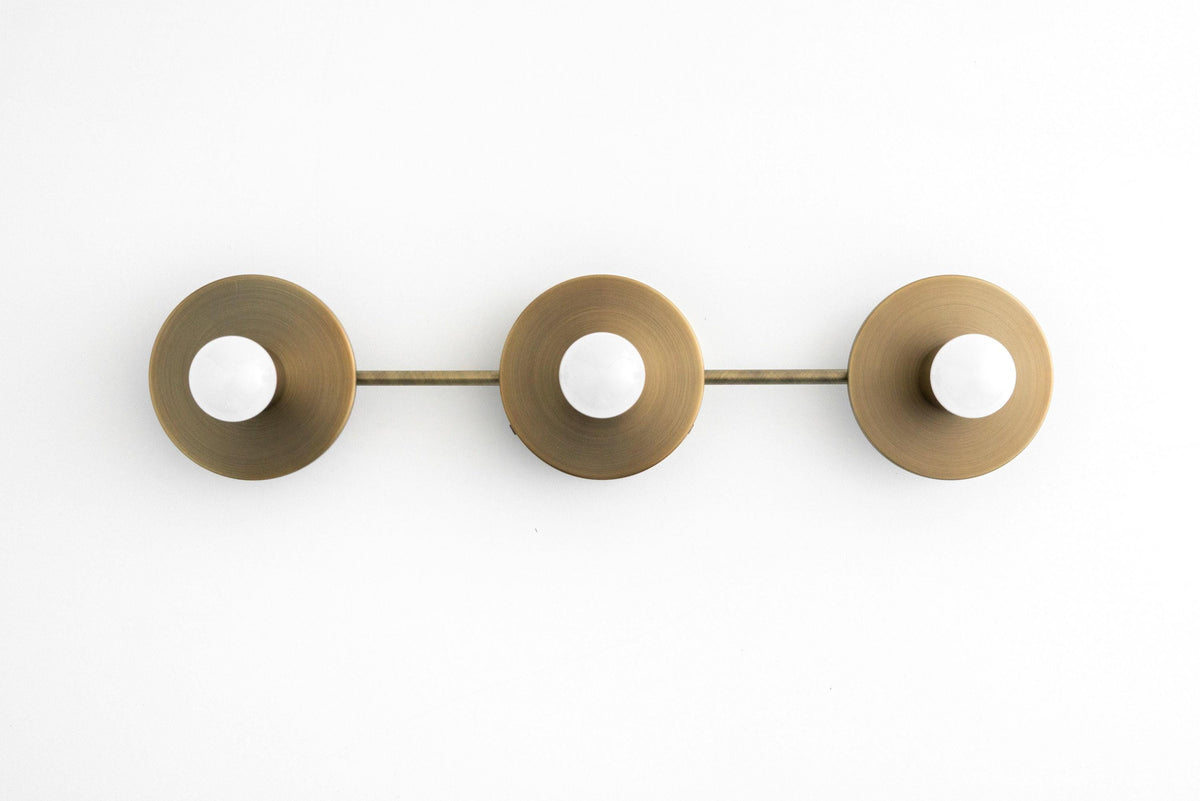 Mid century modern 3-bulb vanity light in antique brass with bare round bulbs and circular backplates. - VANITY LIGHT MODEL NO. 5708