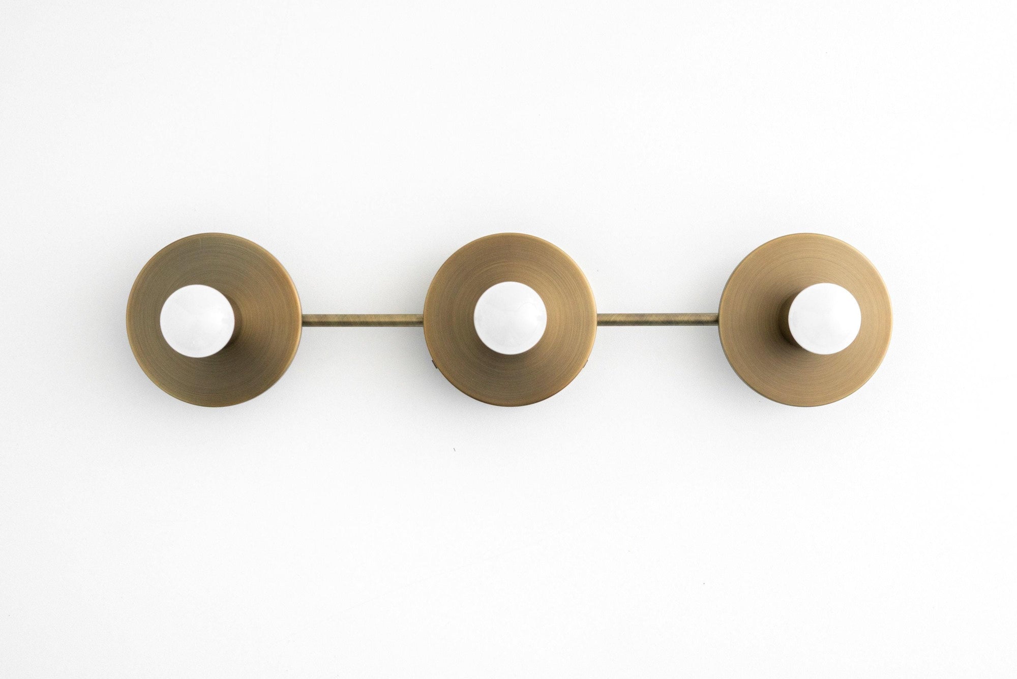 Mid century modern 3-bulb vanity light in antique brass with bare round bulbs and circular backplates. - VANITY LIGHT MODEL NO. 5708