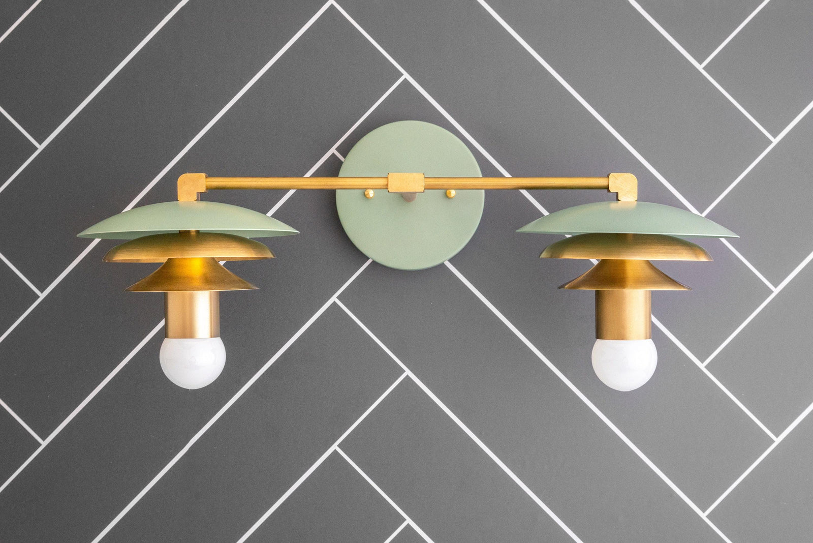 Raw brass and muted green two-bulb vanity light with layered Art Deco shades on black tile wall. - VANITY LIGHT MODEL NO. 5806