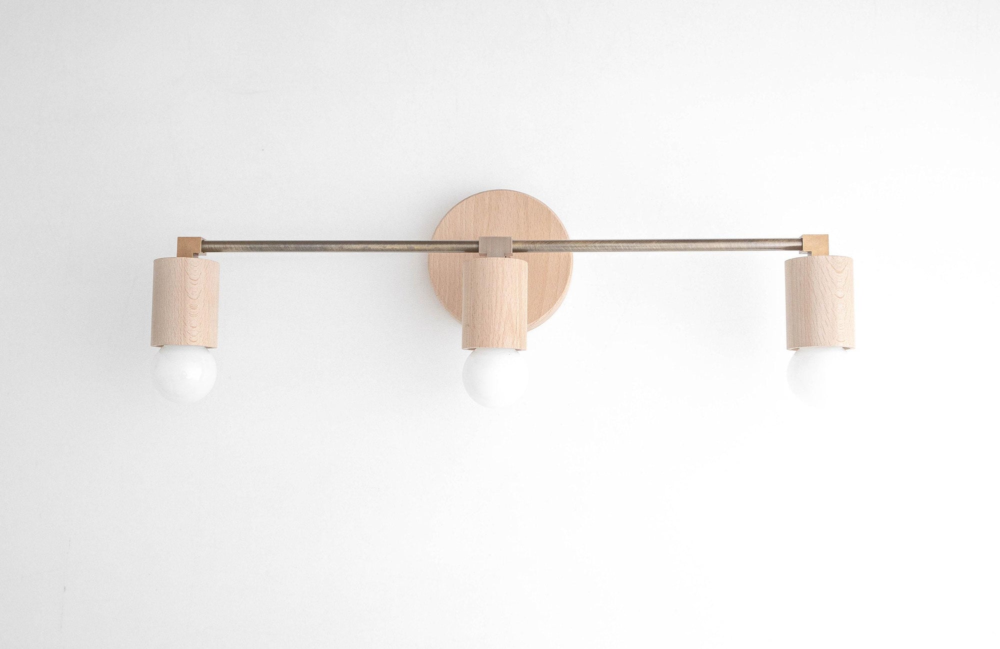 Three-bulb vanity light with natural beech wood and black metal rod mounted on white wall. - VANITY LIGHT MODEL NO. 4446