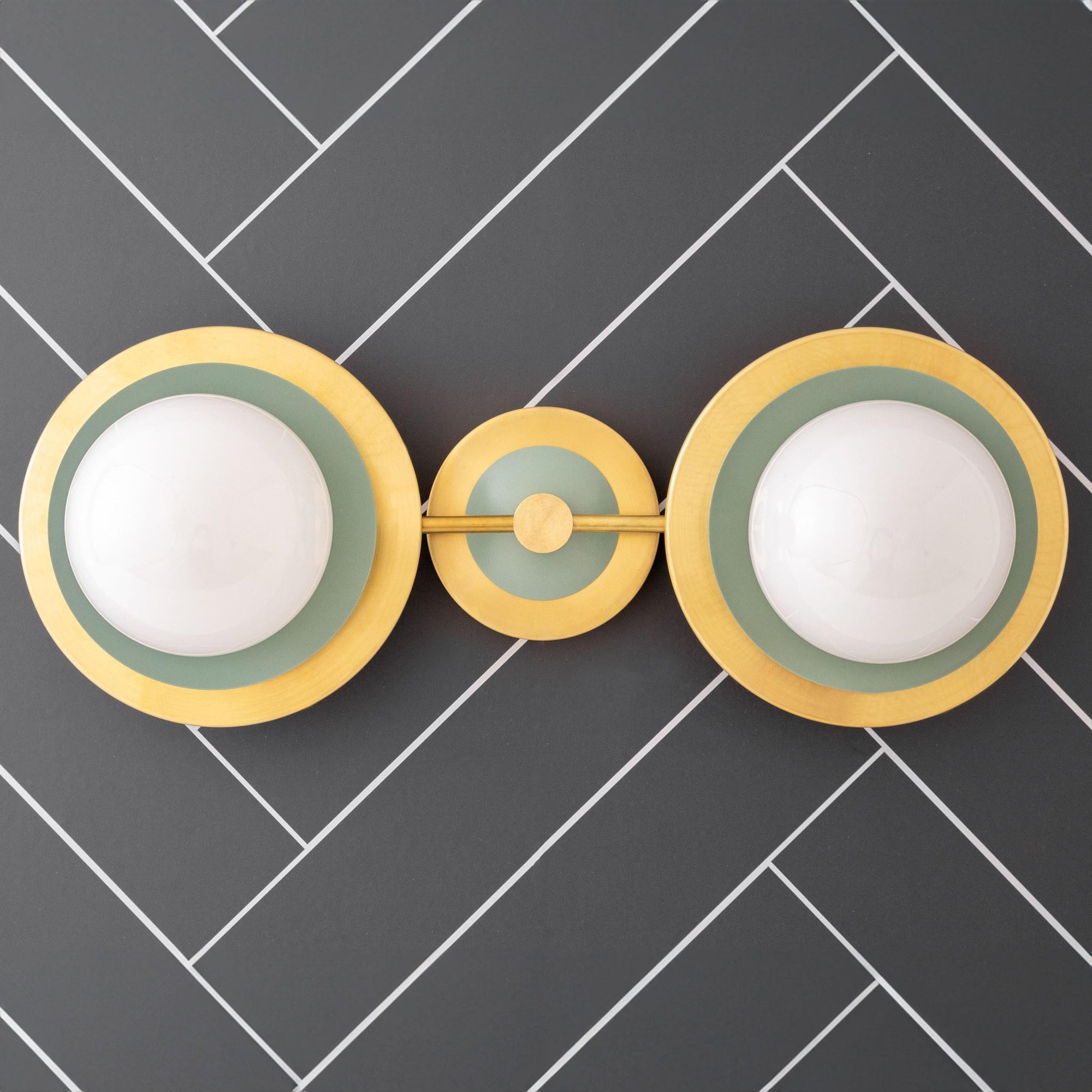 Mid-century modern vanity light with two white globe bulbs and raw brass and green accents on dark herringbone wall. - VANITY LIGHT MODEL NO. 9361