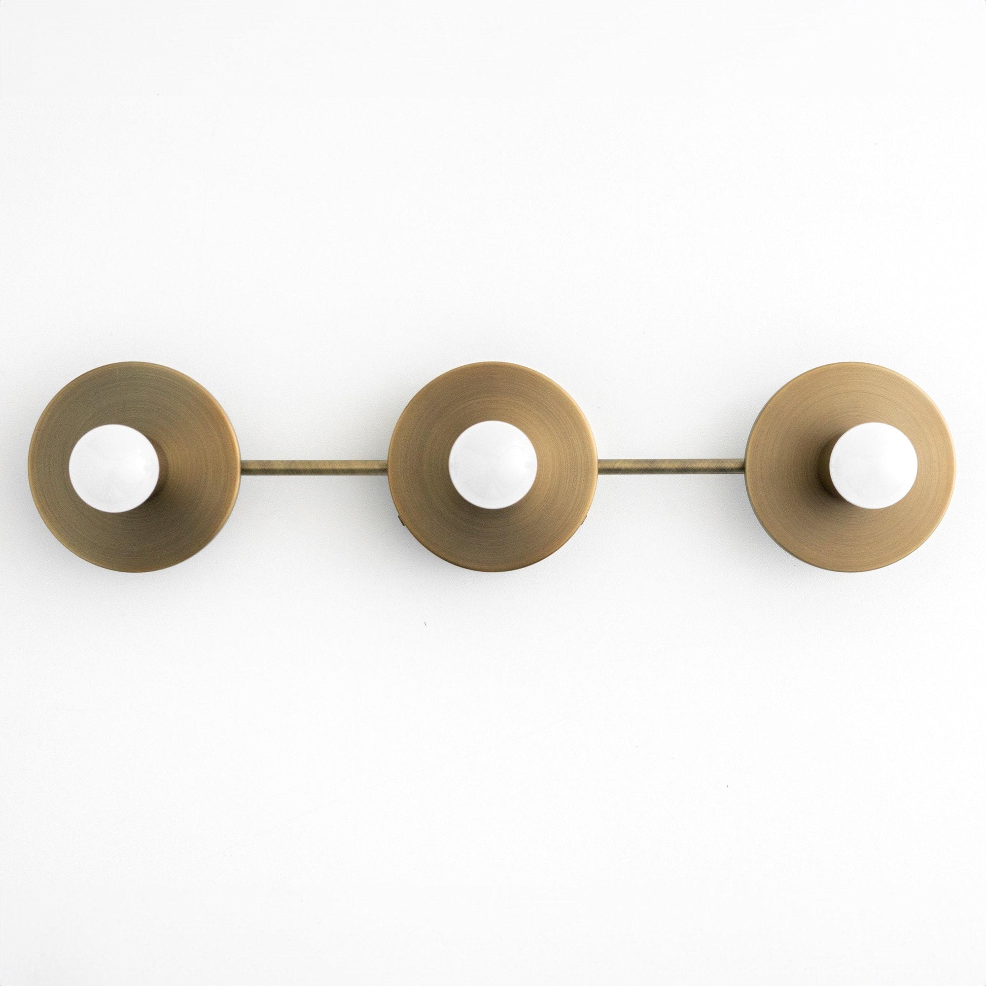 Three-bulb vanity light fixture in antique brass with round, dome-shaped shades and exposed bulbs. - VANITY LIGHT MODEL NO. 5708