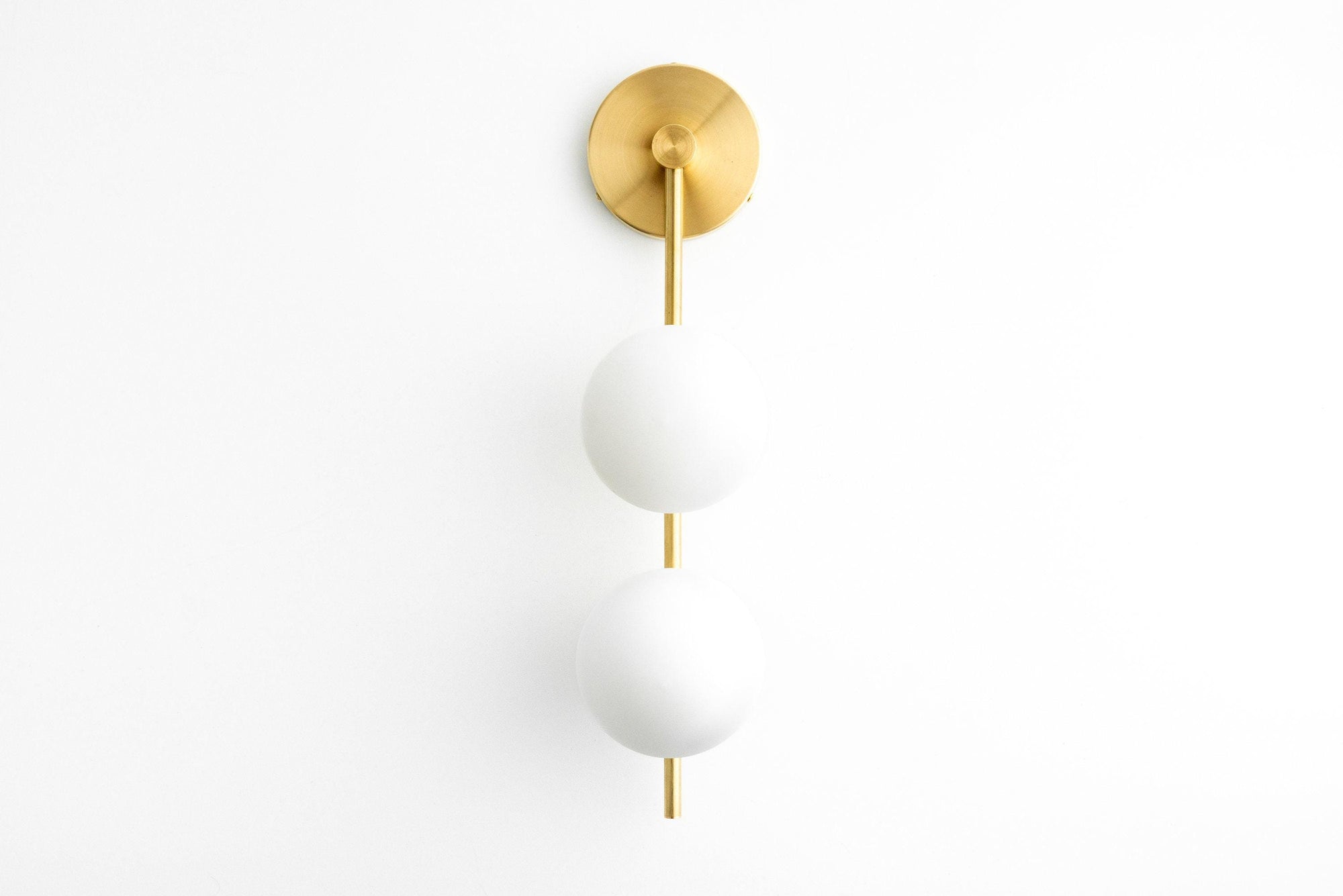 Mid-century modern drop sconce with two white glass globes and antique brass mounting plate. - SCONCE MODEL NO. 0344